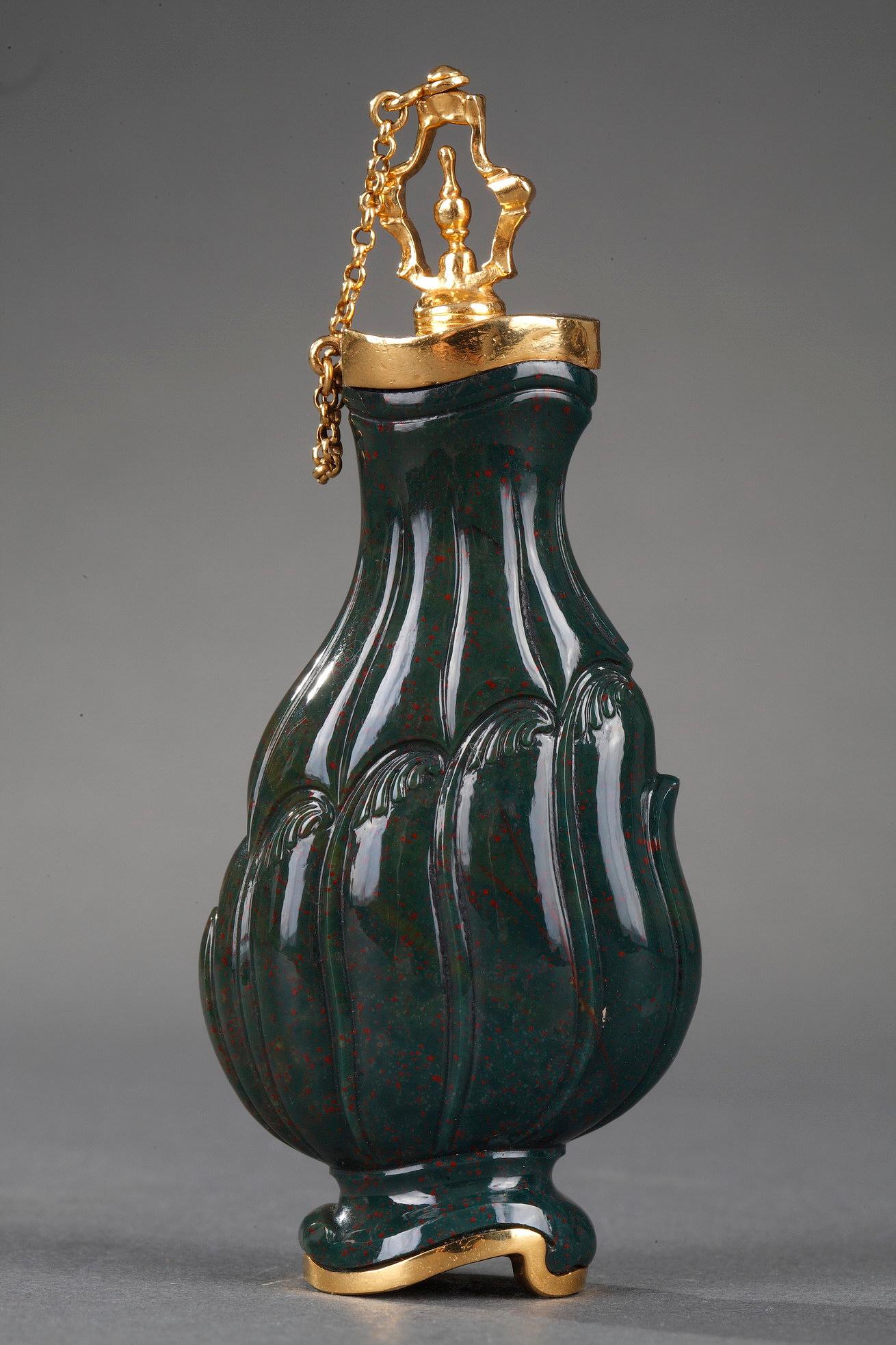 Exceptional pear-shaped flask in heliotrope, also known as bloodstone jasper. The body of the flask intricately sculpted with gadrooning and Rocaille motifs. A band of gold encircles the neck and base of the flask, and the openwork, gold stopper is