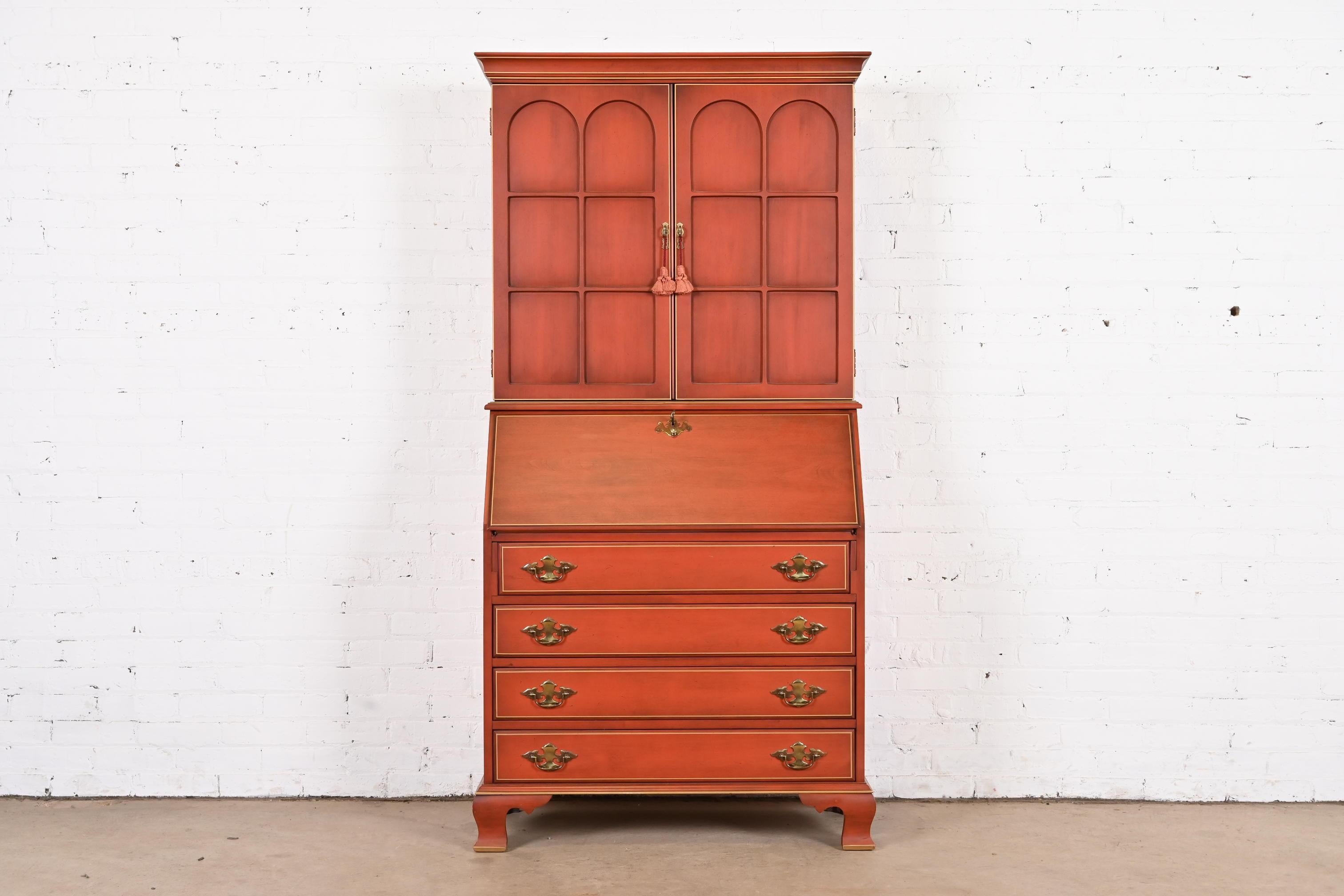 A gorgeous Georgian or Chippendale style bureau with drop front secretary desk and bookcase hutch top

By Jasper Cabinet Co.

USA, Circa 1970s

Carved red lacquered cherry wood, with gold gilt trim, and original brass hardware. Desk locks, and