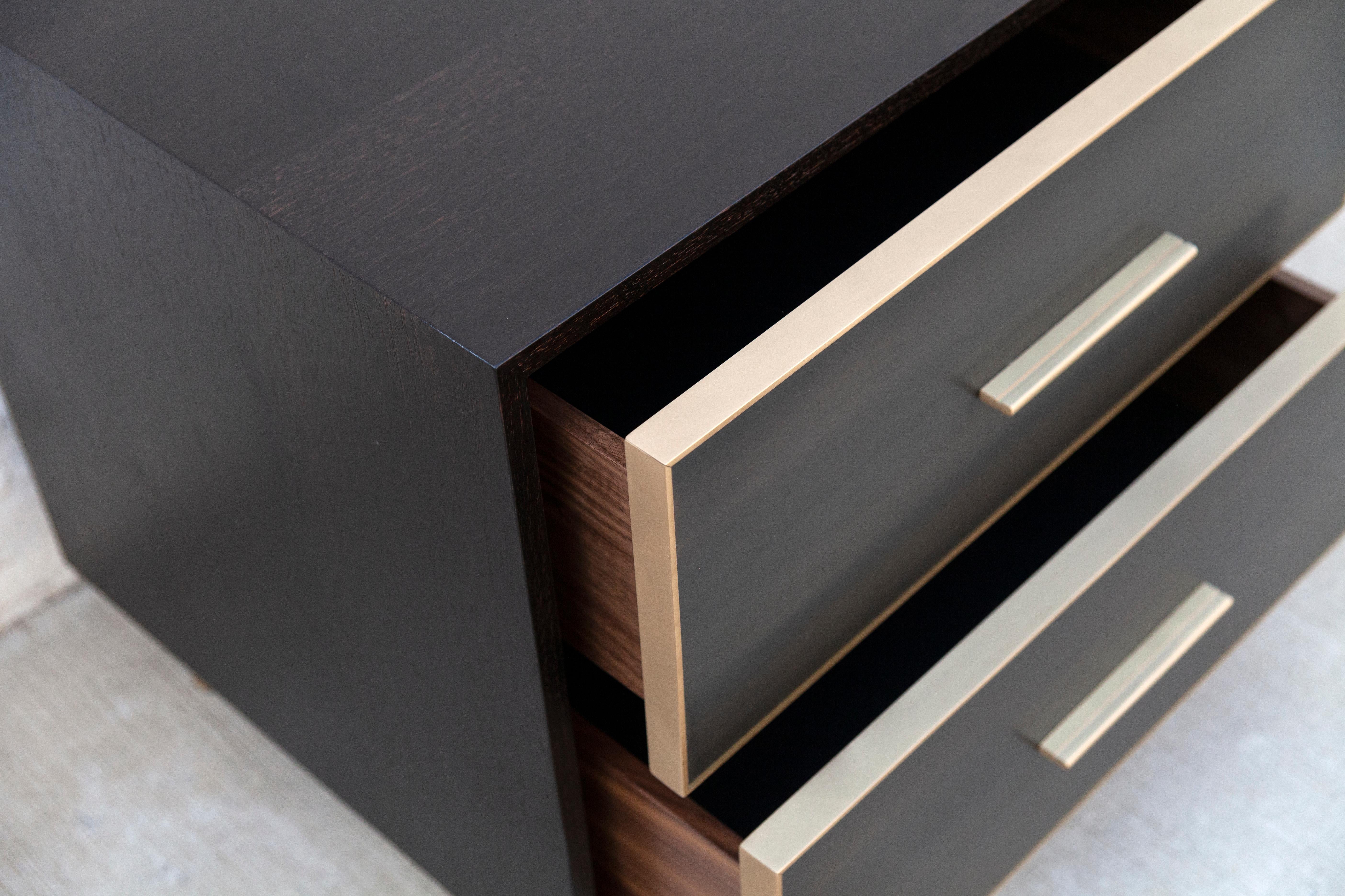 Compacte mais convaincante, la table d'appoint Jasper oppose des surfaces lisses et texturées, avec des tiroirs en résine de bronze coulés dans un extérieur en bois oxydé. La simplicité et la sobriété du design dissimulent un merveilleux mélange de
