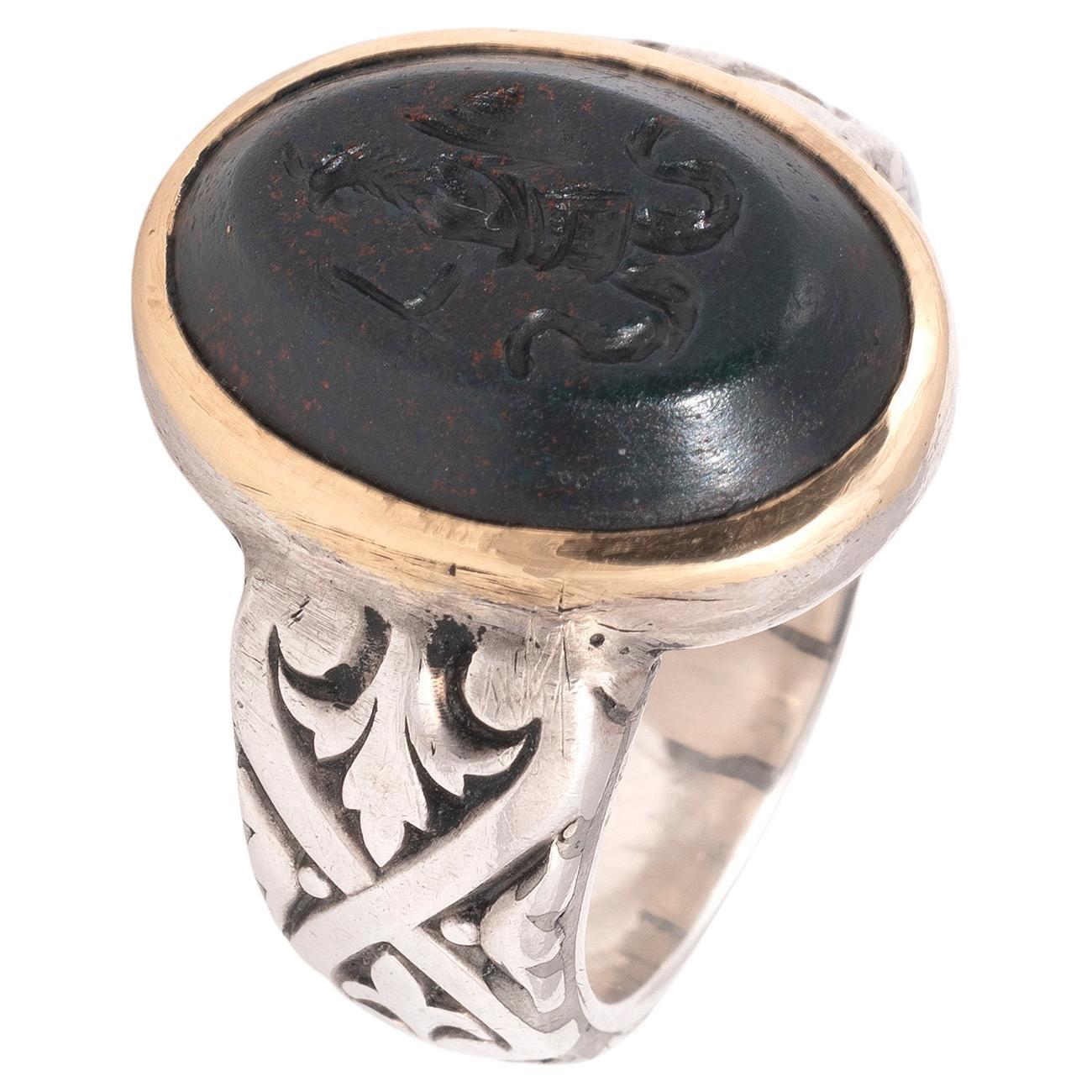 Ring in 18kt yellow gold and silver decorated with a heliotrope jasper intaglio engraved with an Abraxas in the form of an alectorocephalic anguipede holding a shield and a spear. These kind of stones were used in antiquity to repel the demons and
