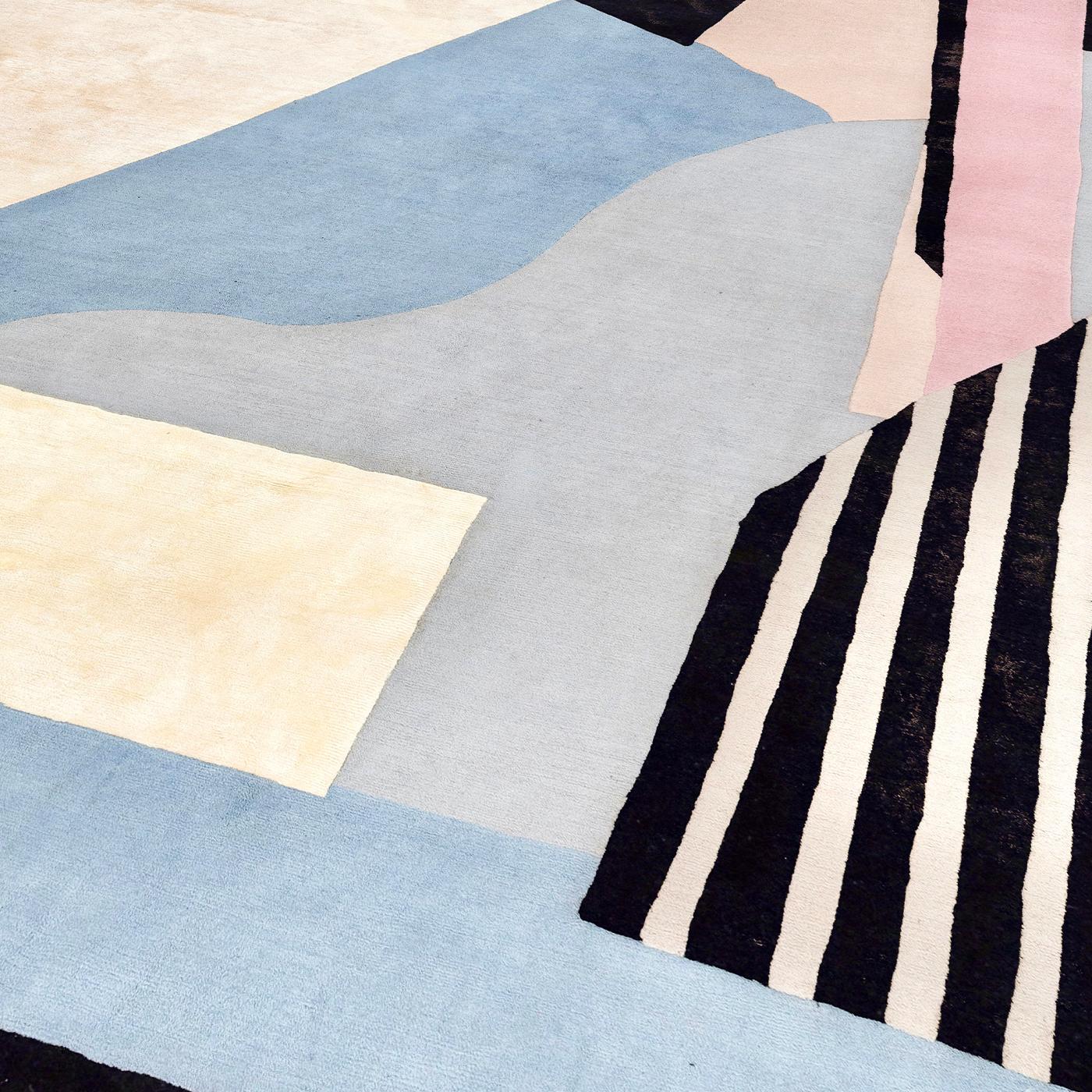 A true textile artwork paying homage to the avant-garde Dada, this rug boasts an abstract pattern in a delightful combination of azure, pink, and beige, only interrupted by black lines. It is handcrafted by Nepalese weavers of 50% silk and 50%
