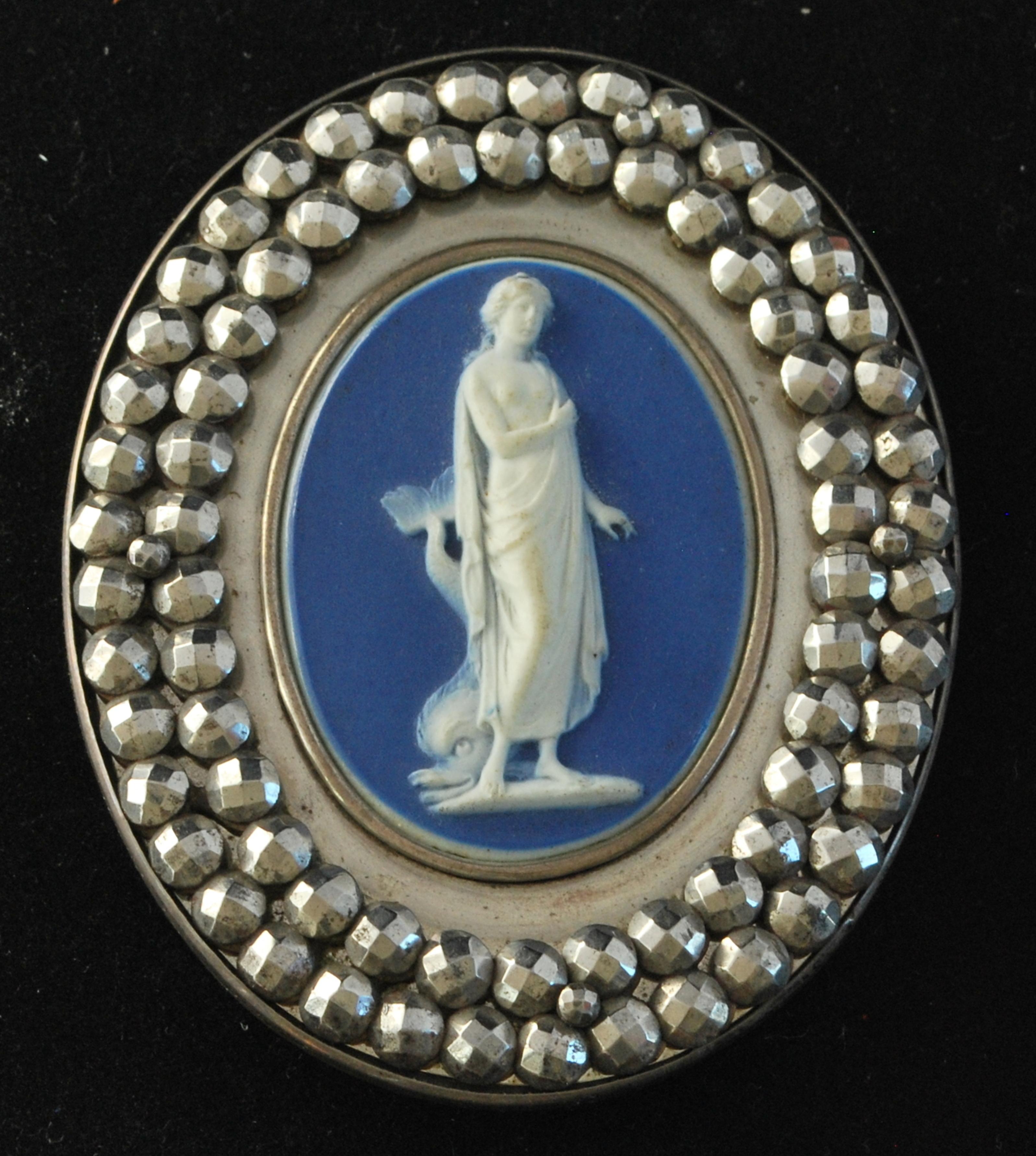 Ein mit Aphrodite verziertes Jaspis-Medaillon, gefasst in geschliffenem Stahl als Schnalle, wahrscheinlich von Matthew Boulton. Originalverpackung.

Die griechische Göttin Aphrodite wird in der antiken Kunst oft mit einem Delphin abgebildet. In der