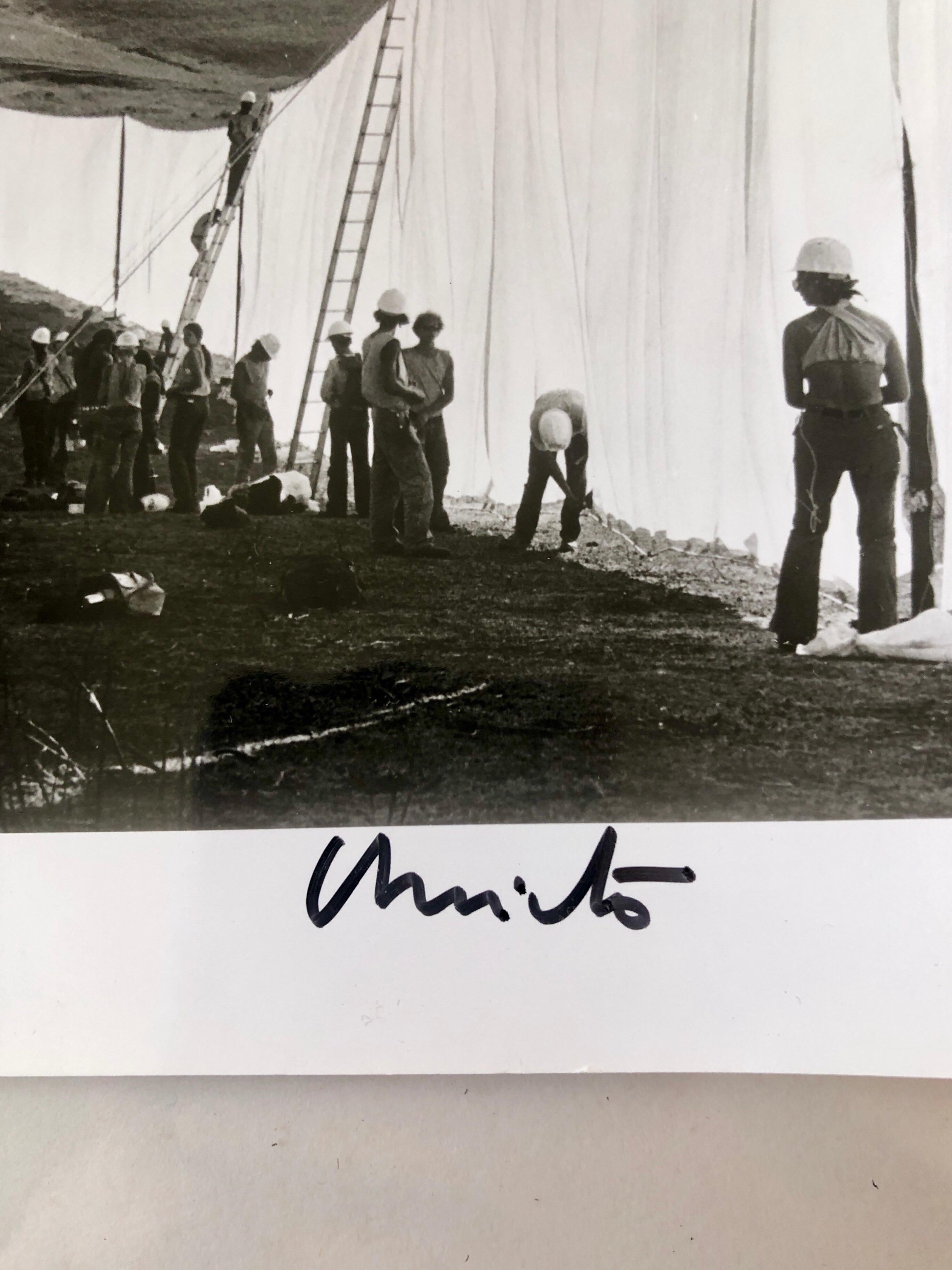 This is a vintage print of Christo working on the Running Fence Project.  it is hand signed and stamped with the Christo project stamp and Wolfgang Volz studio stamp. 
Running Fence was an installation art piece by Christo and Jeanne-Claude, which