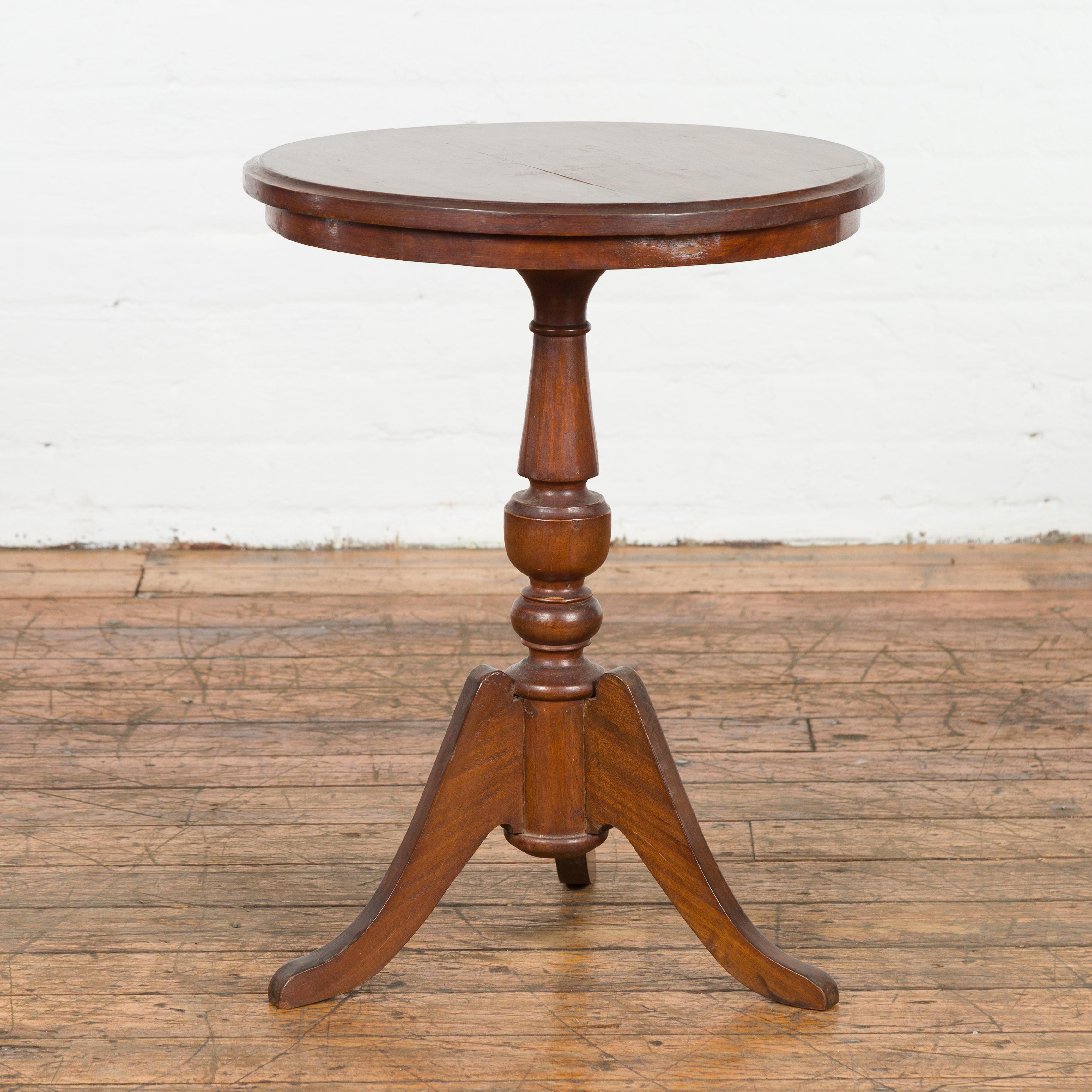 A Javanese wooden guéridon side table from the early 20th century, with circular top, turned pedestal and tripod base. Created on the island of Java during the early years of the 20th century, this wooden accent table features a round top with