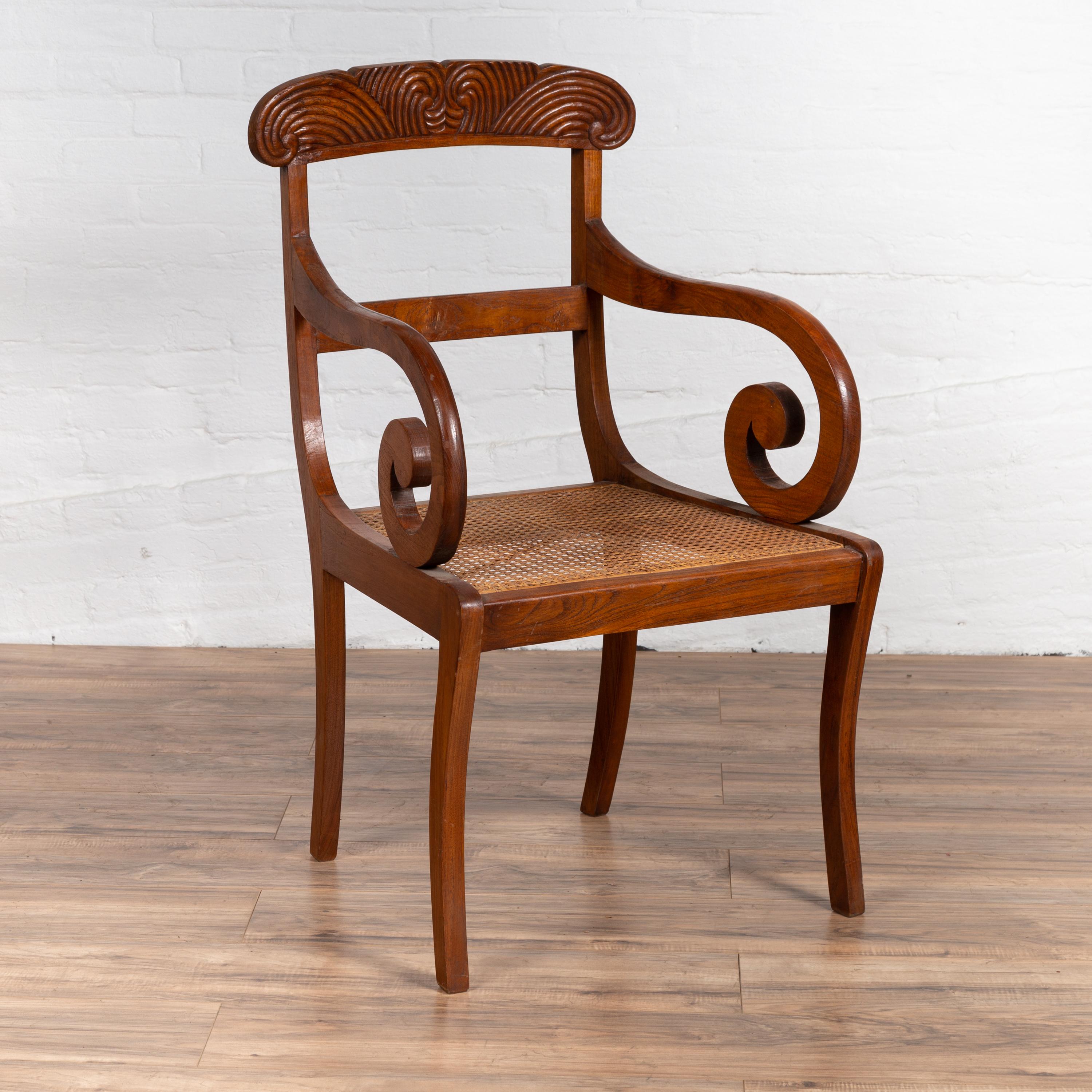 An antique Javanese wooden armchair from the early 20th century with carved back, curving arms and woven rattan seat. We have a near pair available, please view our other chair LU863915598432 as well as image #3 that shows both of them together