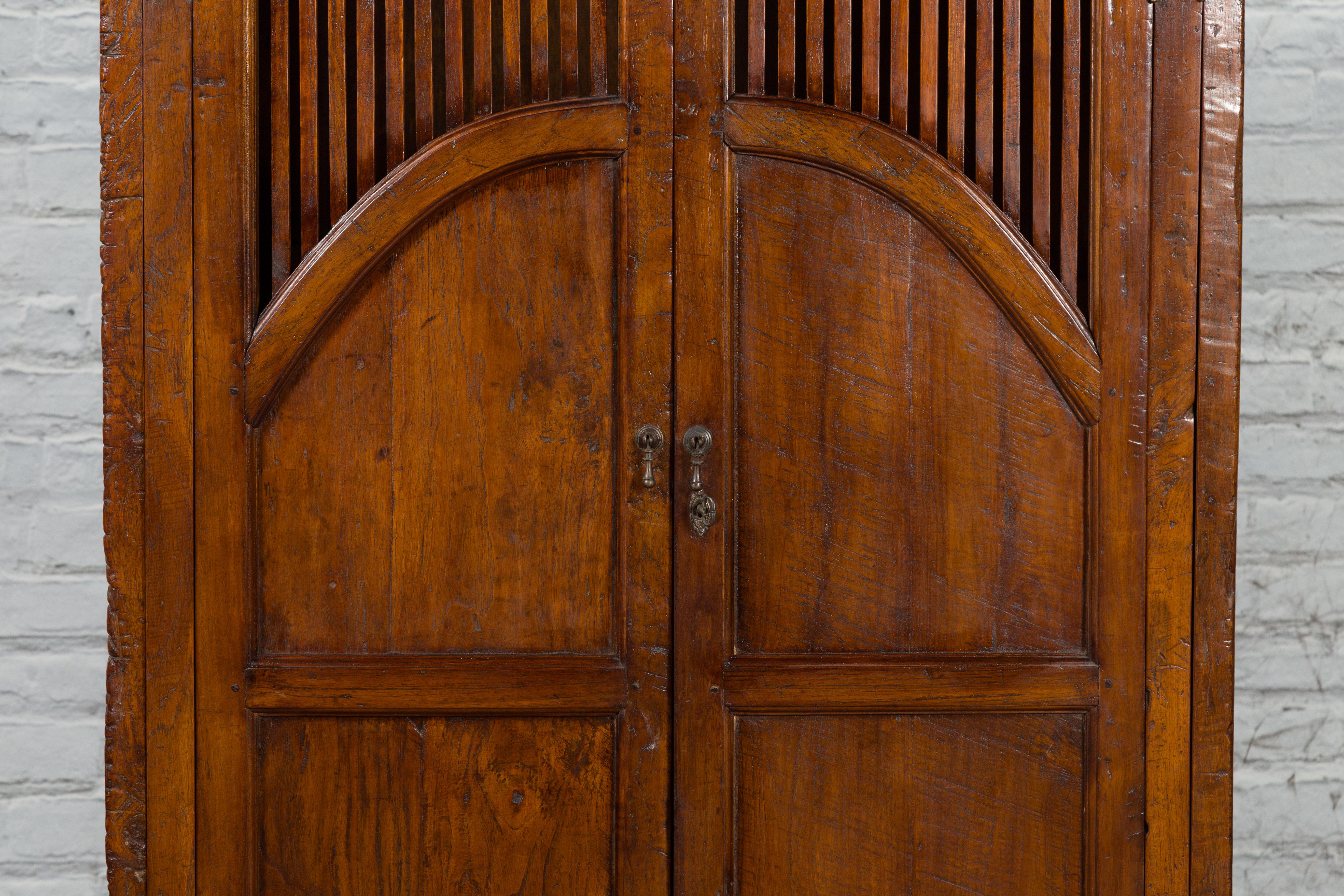 Rustic Javanese Antique Teak Armoire with Slatted Motifs, Tapered Feet and Patina For Sale