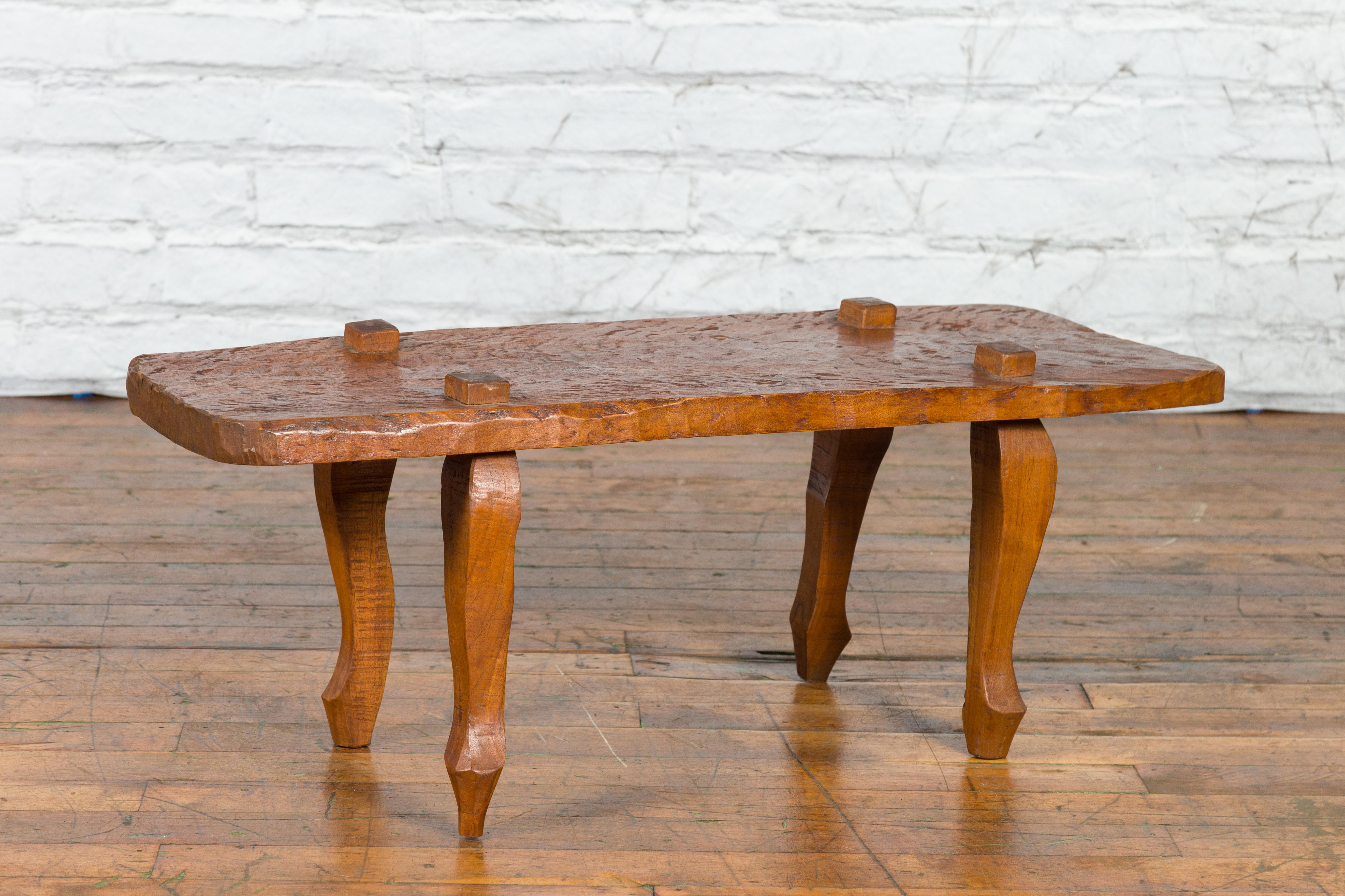 A Javanese Arts & Crafts teak low table / bench from the early 20th century, with carved recessed legs. Created in Java during the early years of the 20th century, this Arts & Crafts teak table features an irregular rectangular top with raised