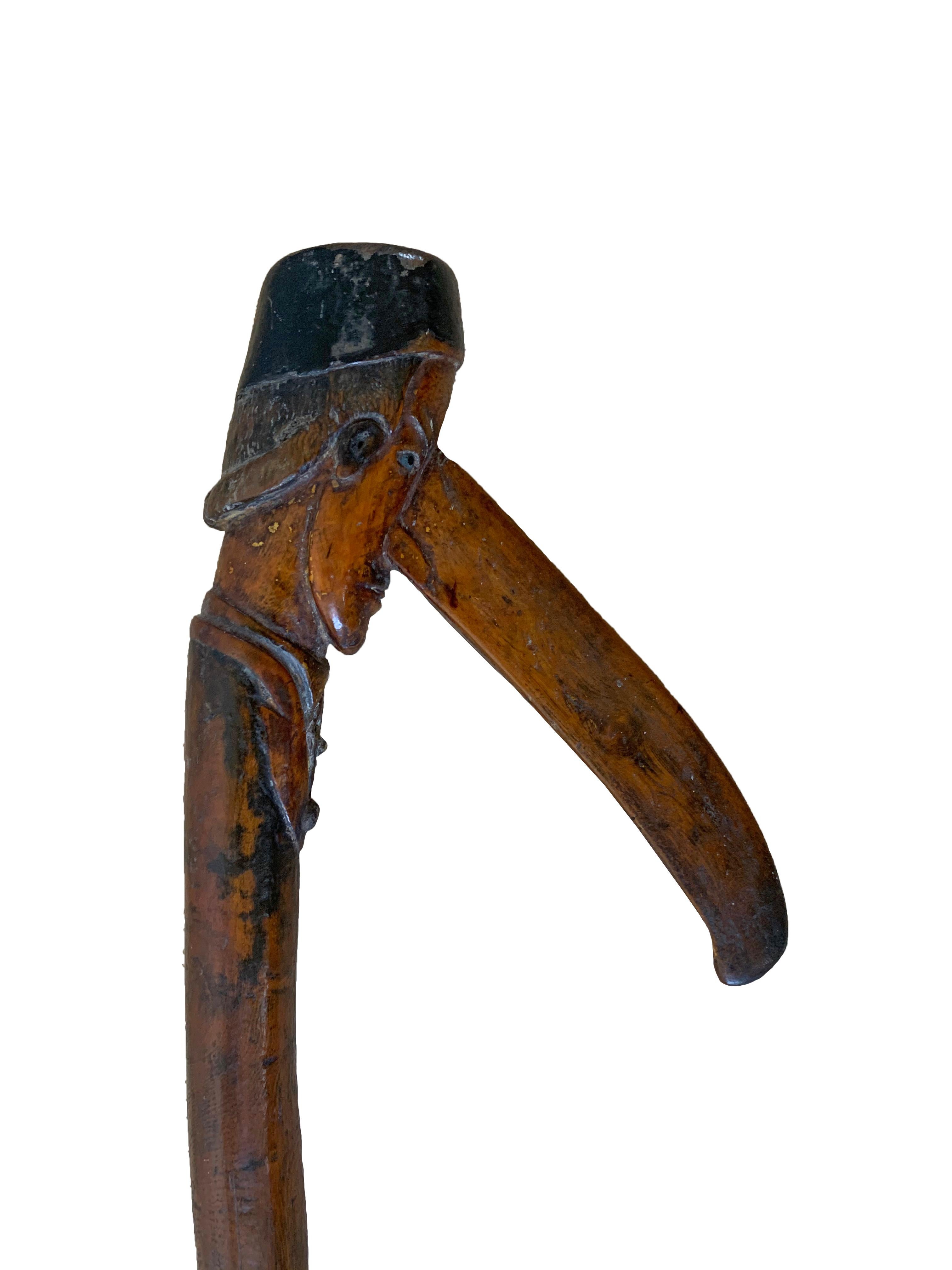This hand-crafted walking stick originates from the island of Java, Indonesia around the turn of the 19th Century. It features hand-carved detailing of a male figure with an extraordinarily long nose. A unique item certain to invoke conversation.