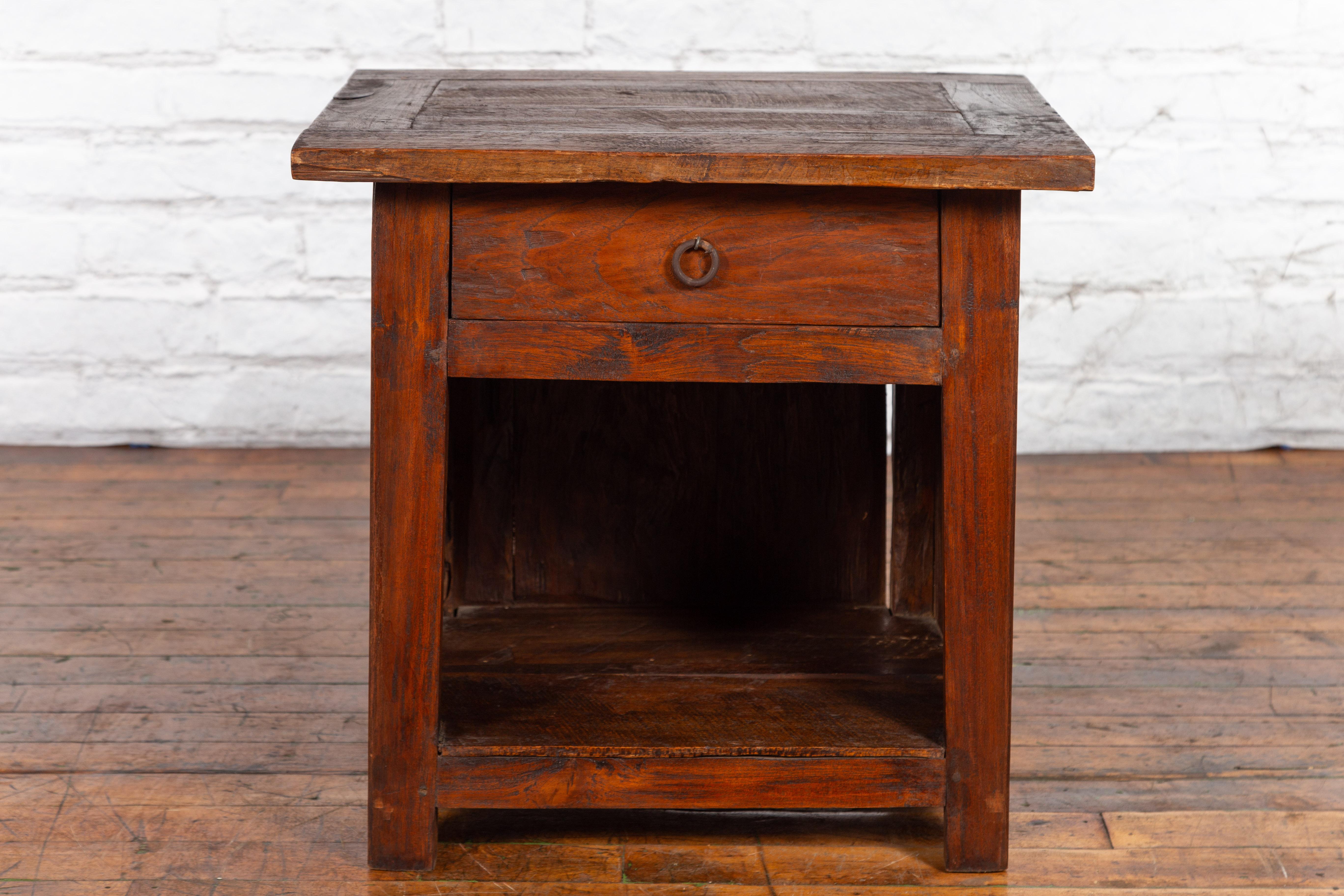 An antique Javanese wooden bedside cabinet from the early 20th century, with single drawer, open shelf and nice patina. Created on the Indonesian island of Java during the early years of the 20th century, this wooden bedside cabinet features a