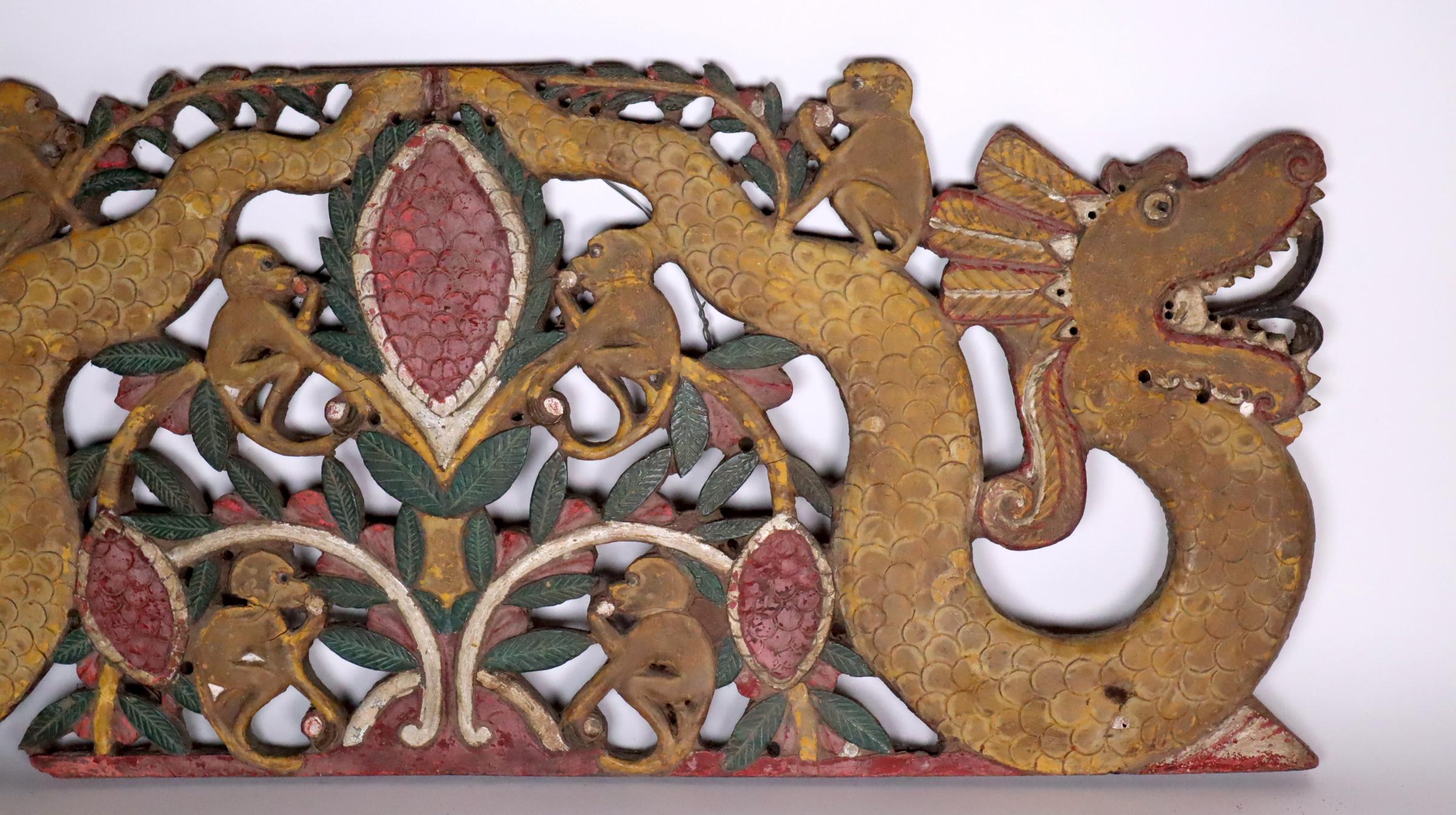 Large colorful painted hardwood plaque from Java, Indonesia. Probably early 20th century. Depicts a fruiting and leafing plant with two large serpents (called naga) wearing feathered crowns, their mouths are open showing teeth and forked tongue. Six