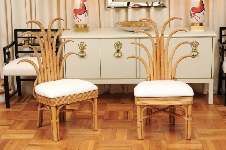 An absolutely majestic set of twelve (12) custom made palm frond style dining chairs, circa 1950. Exceptionally conceived and crafted rattan and hardwood construction with a magnificent back detail. Stout, rigid and comfortable, built for heavy