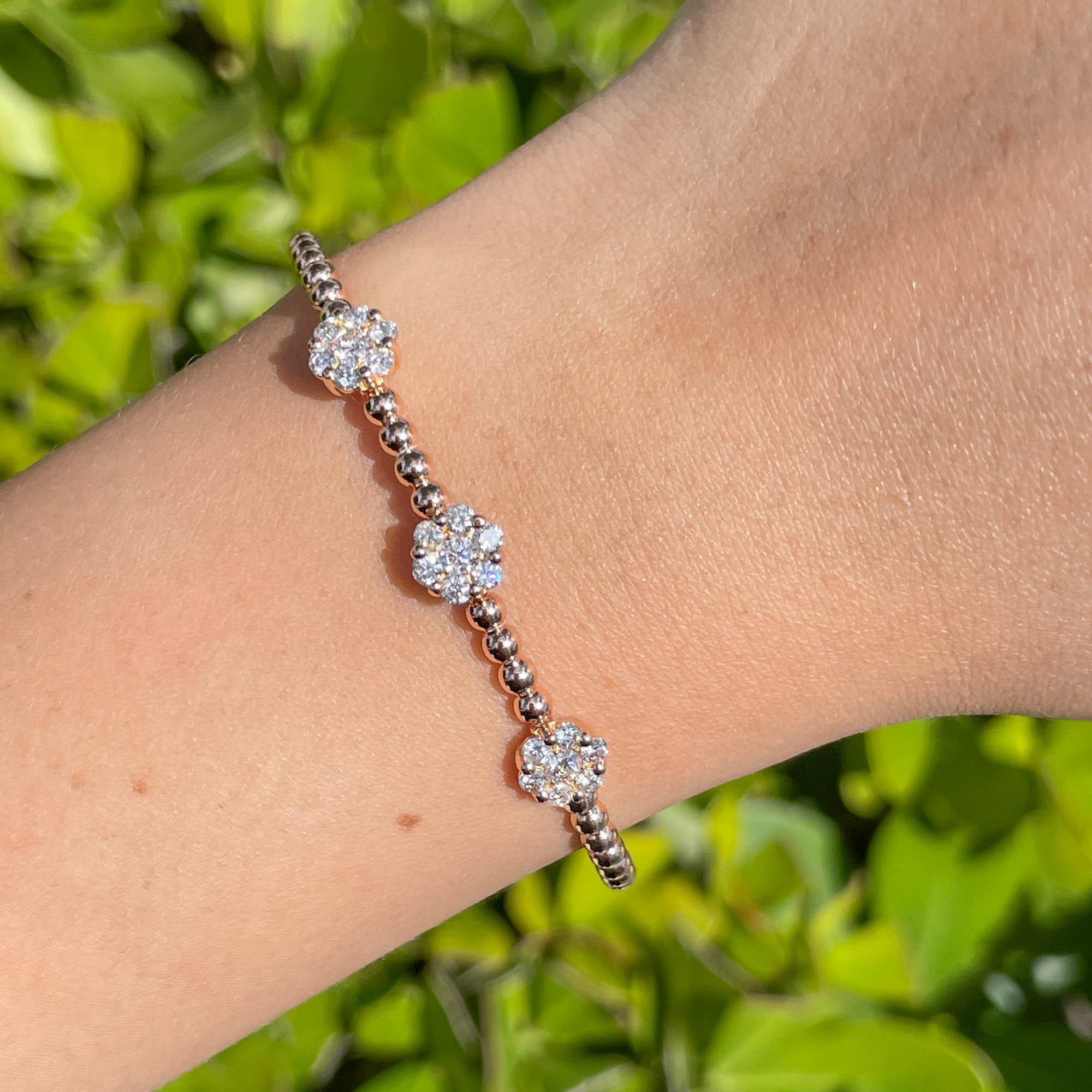 Bracciale Jay Feder in oro rosa 18k con diamanti e 3 fiori a grappolo

Con 21 diamanti tondi brillanti incastonati; il peso totale è di 1,20 carati.

Il bracciale ha un diametro di 2,5 pollici e il fiore è largo 7,23 mm. Il peso totale è di 8,9