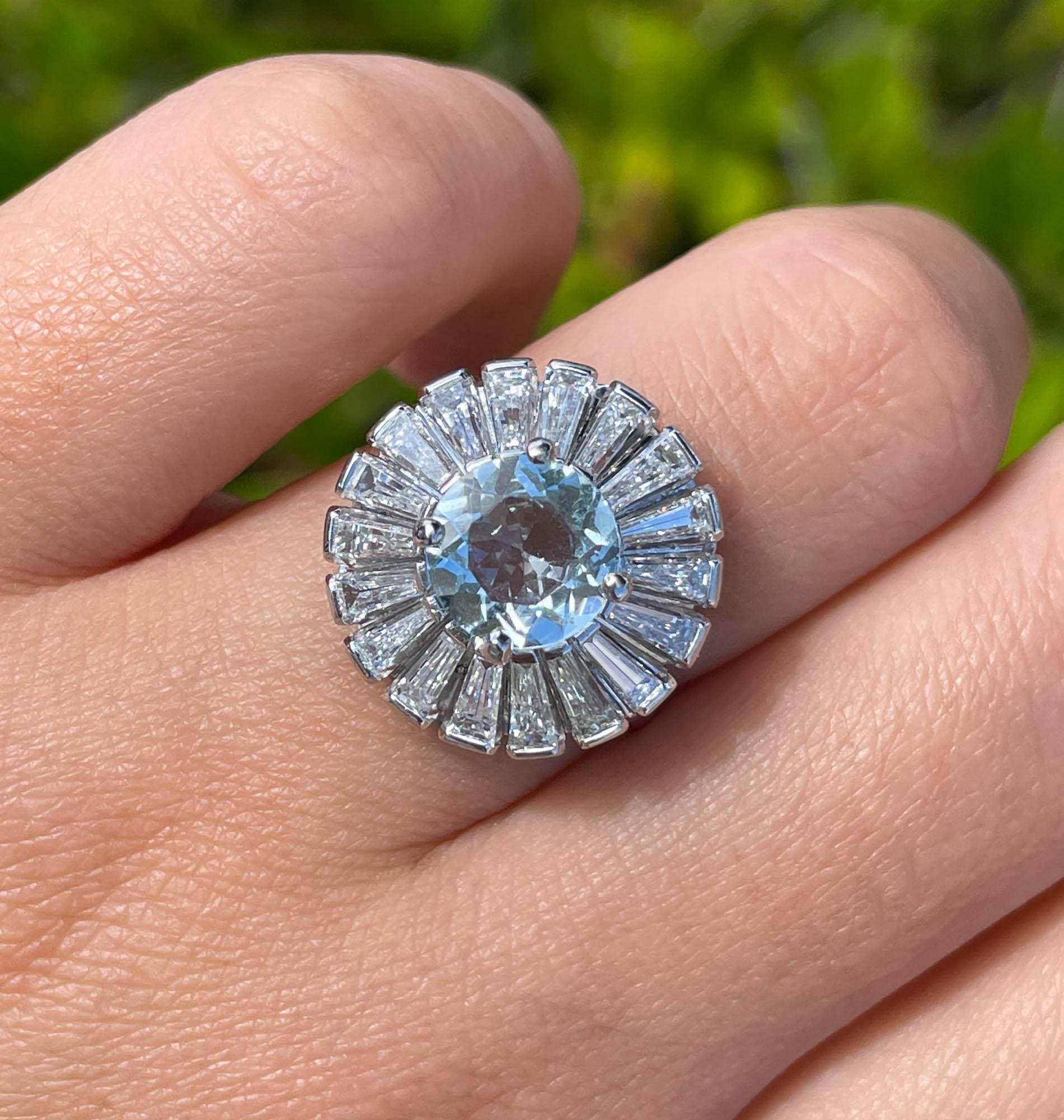 Jay Feder Platinum Aquamarine and Diamond Ballerina Cluster Ring
The center stone is natural round shaped aquamarine; measures to 8mm in diameter; estimated weight is 1.45 carats.
Set with 18 tapered baguette diamonds; estimated total is approx. 3