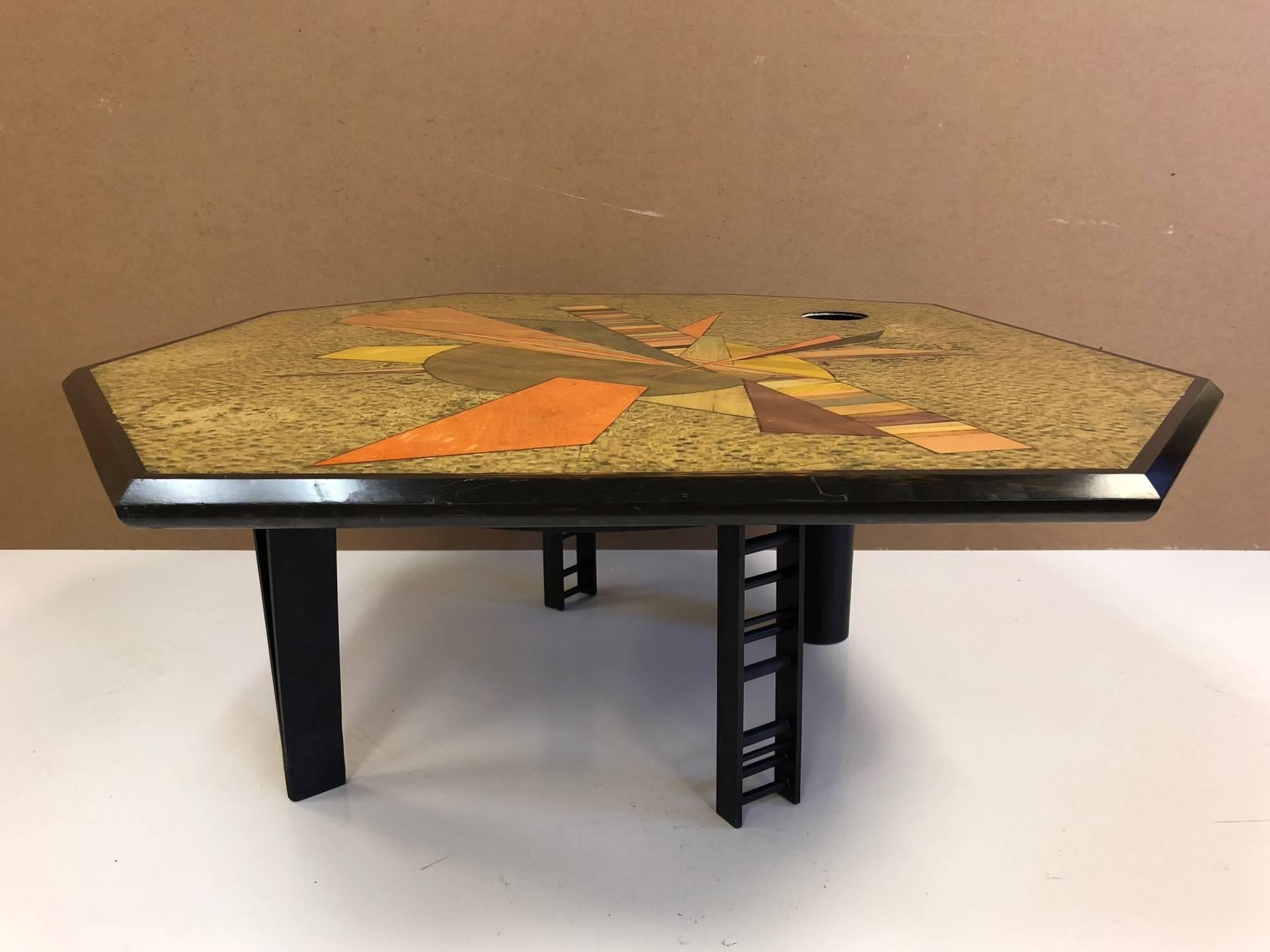 Table basse marquetée signée Jay Stanger, avec des placages teintés sur le dessus et une base en acier peint. La table a une forme géométrique.