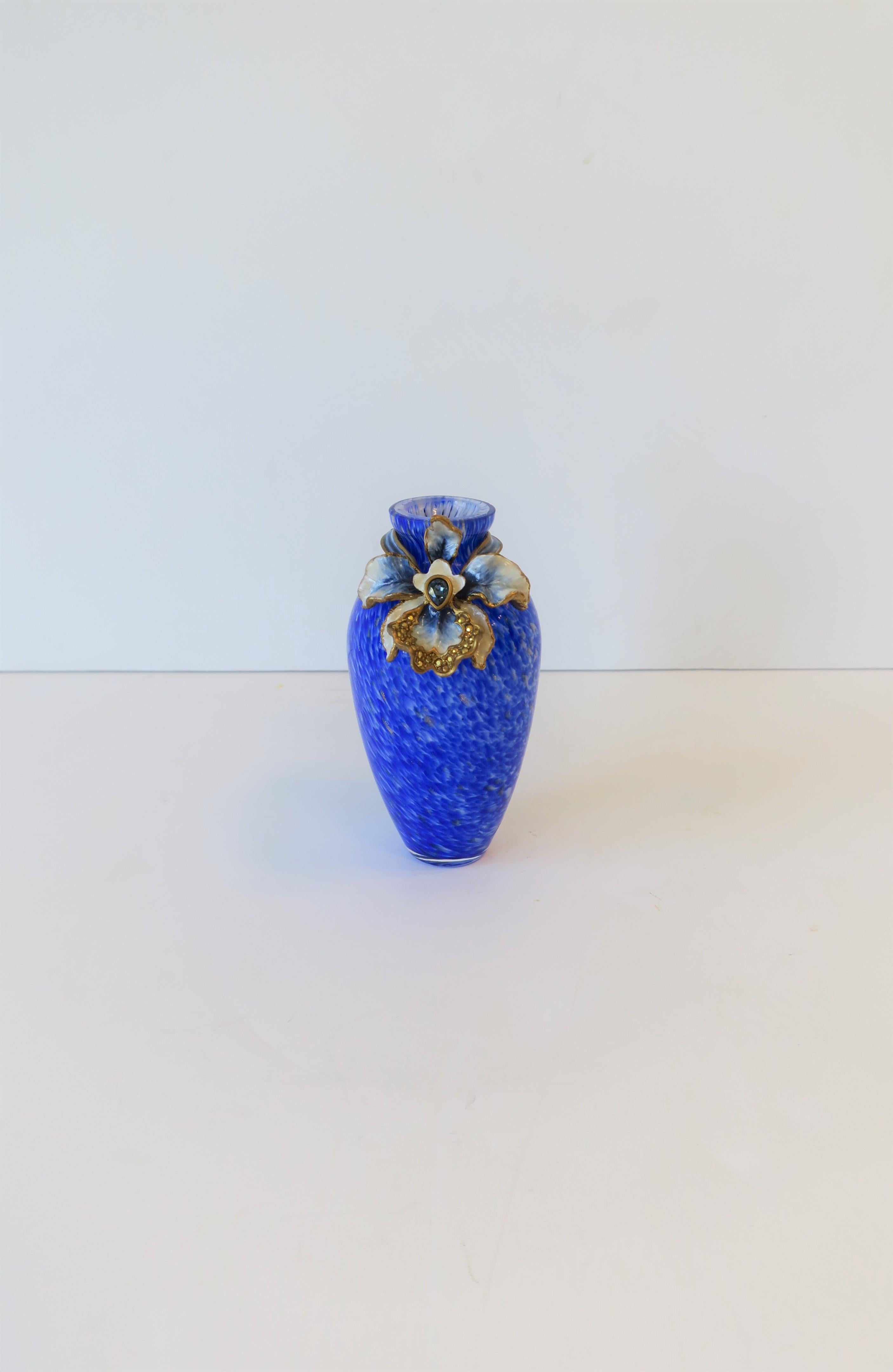 A very beautiful blue, white, and gold, handcrafted vase of hand blown glass by designer Jay Strongwater. A hand painted orchid sculpture surrounds neck is plated in 14-karat gold and embellished with crystals. With maker's mark on back of orchid as