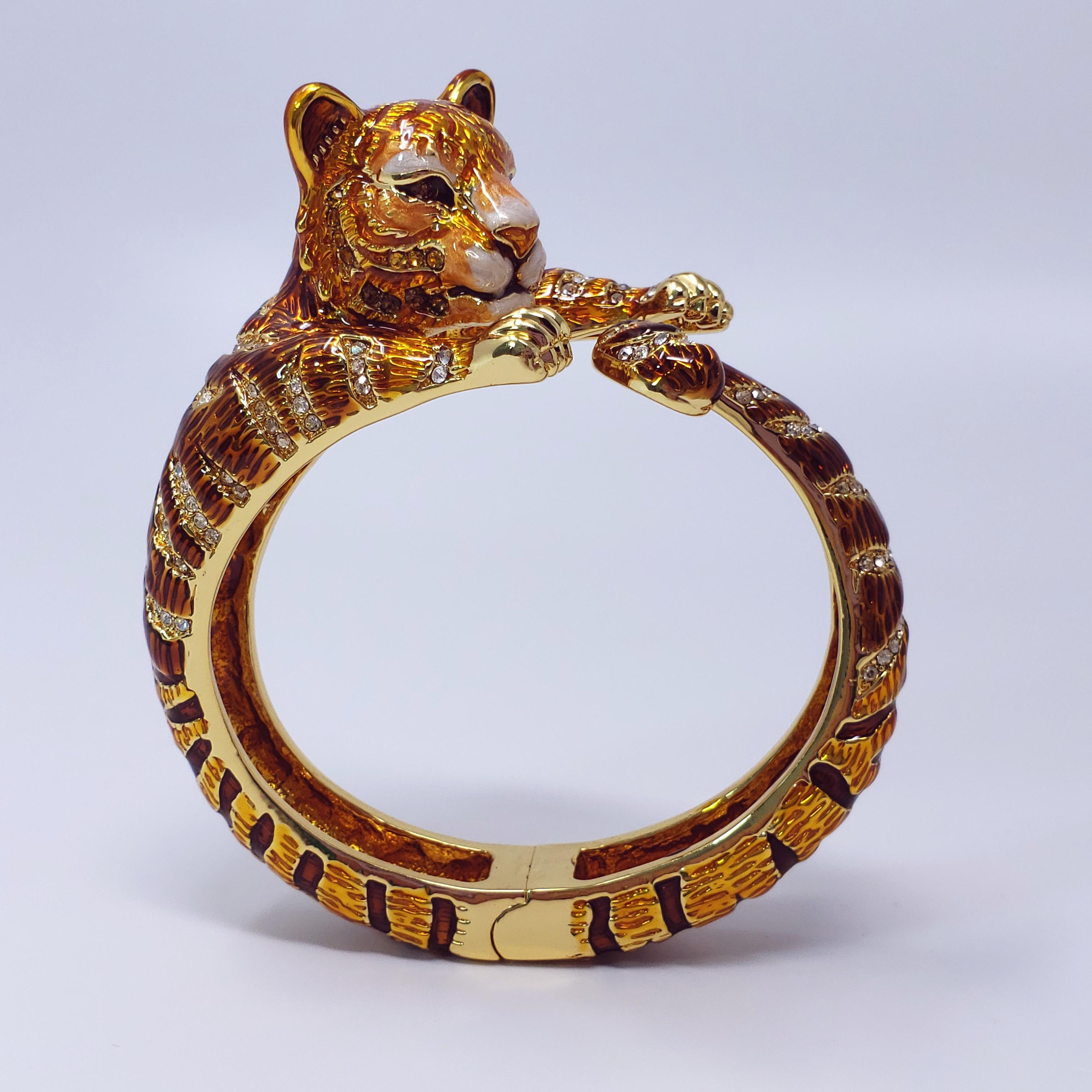 Whimsical Jay Strongwater tiger bracelet. Hand-painted yellow, orange, brown, black, and white enamel. Accented with amber and clear crystals on goldtone metal.

...

Hallmarks: JAY, JAY STRONGWATER, CN

Measurements: 17.2 cm inner circumference,