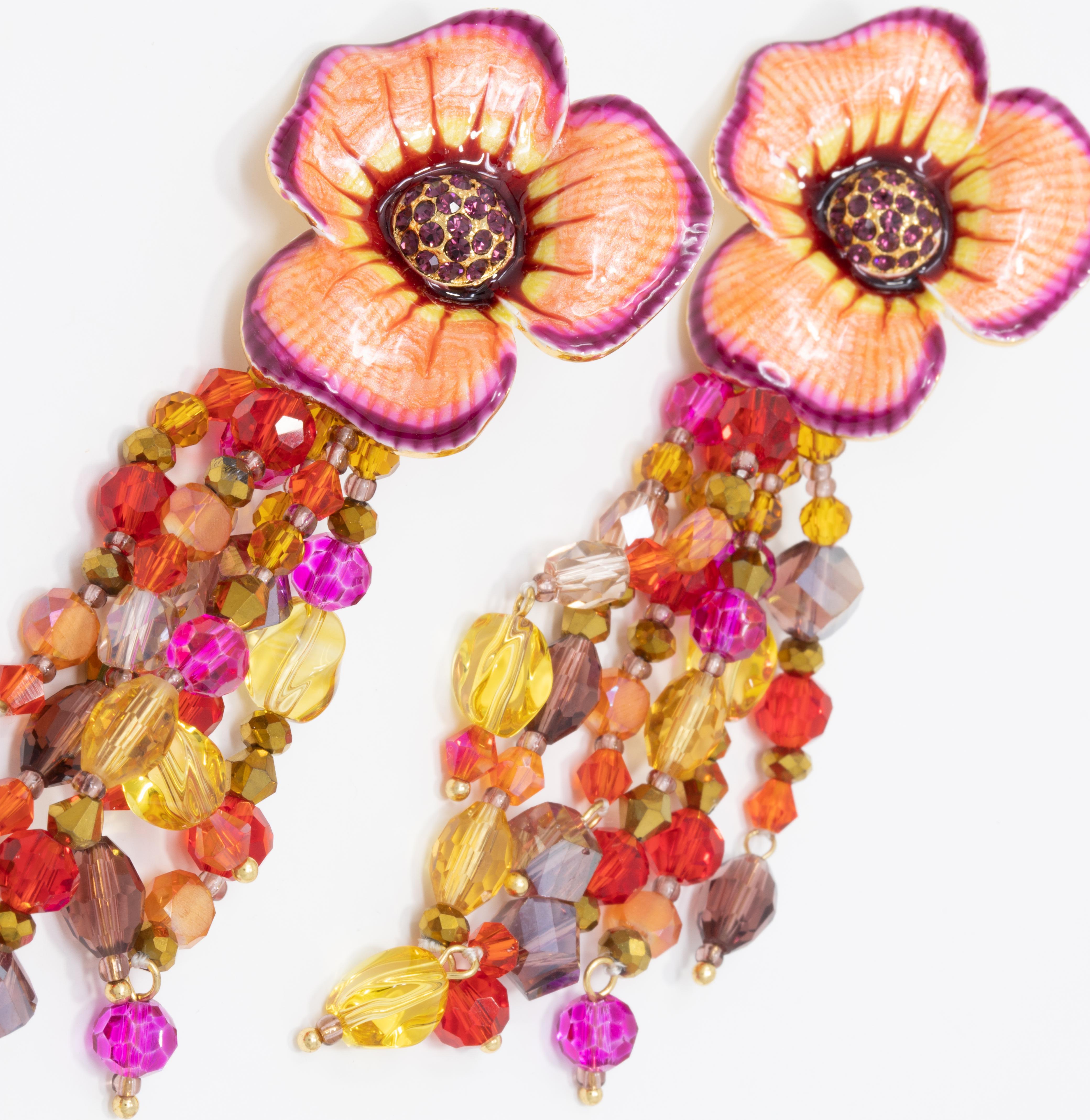 Flower power! A pair of ornate floral clip on earrings featuring dangle ruby, amethyst, and amber crystal strands. Painted peach and purple. Set on gold plated metal.

Hallmarks: Jay, Jay Strongwater, CN

By Jay Strongwater, originally for HSN.