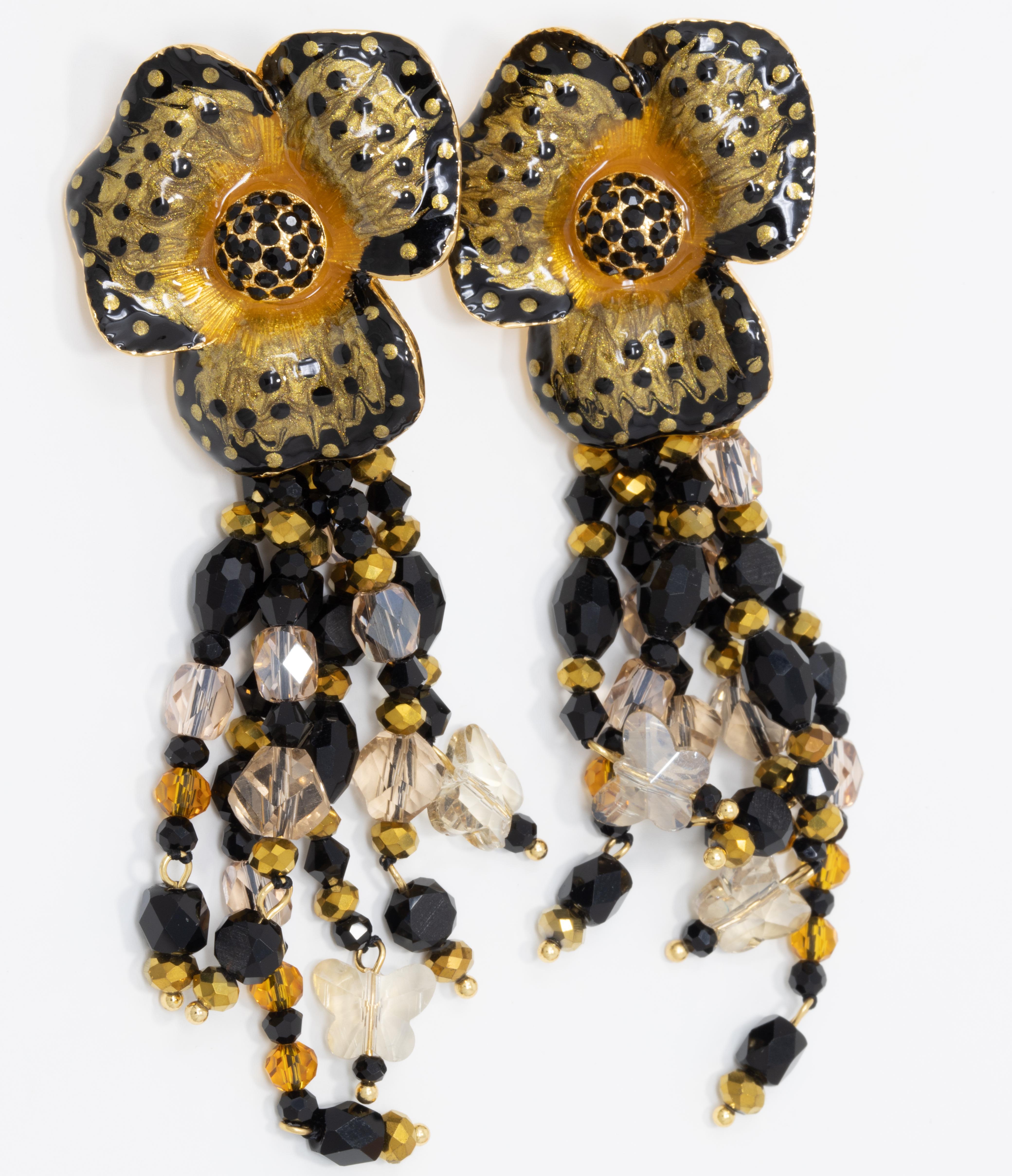 Flower power! A pair of ornate floral clip on earrings featuring dangle jet-black, topaz, and gold crystal strands. Painted with black and yellow enamel. Set on gold plated metal.

Hallmarks: Jay, Jay Strongwater, CN

By Jay Strongwater, originally