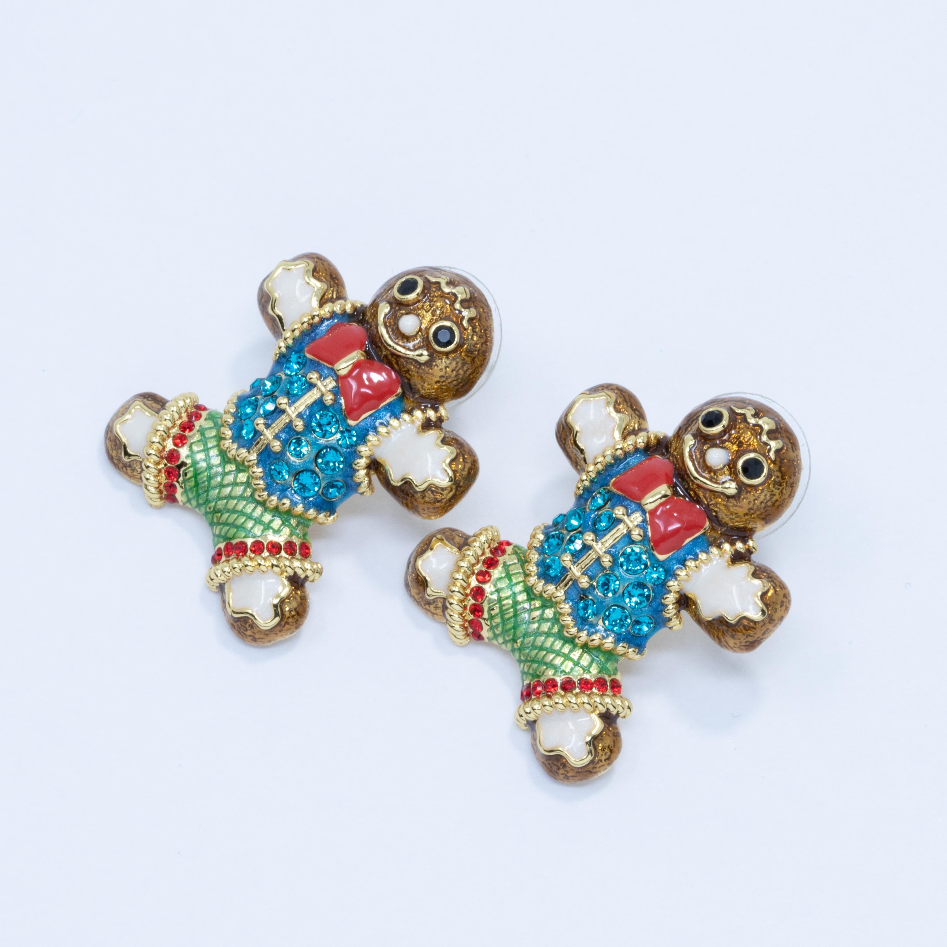 A festive pair of post-back earrings each featuring a gingerbread man enameled with holiday-themed colors and accented with cyan and ruby crystals. Set on gold-plated metal.

Enamel colors: Red, Brown, Green, White

Hallmarks: Jay, Jay Strongwater,