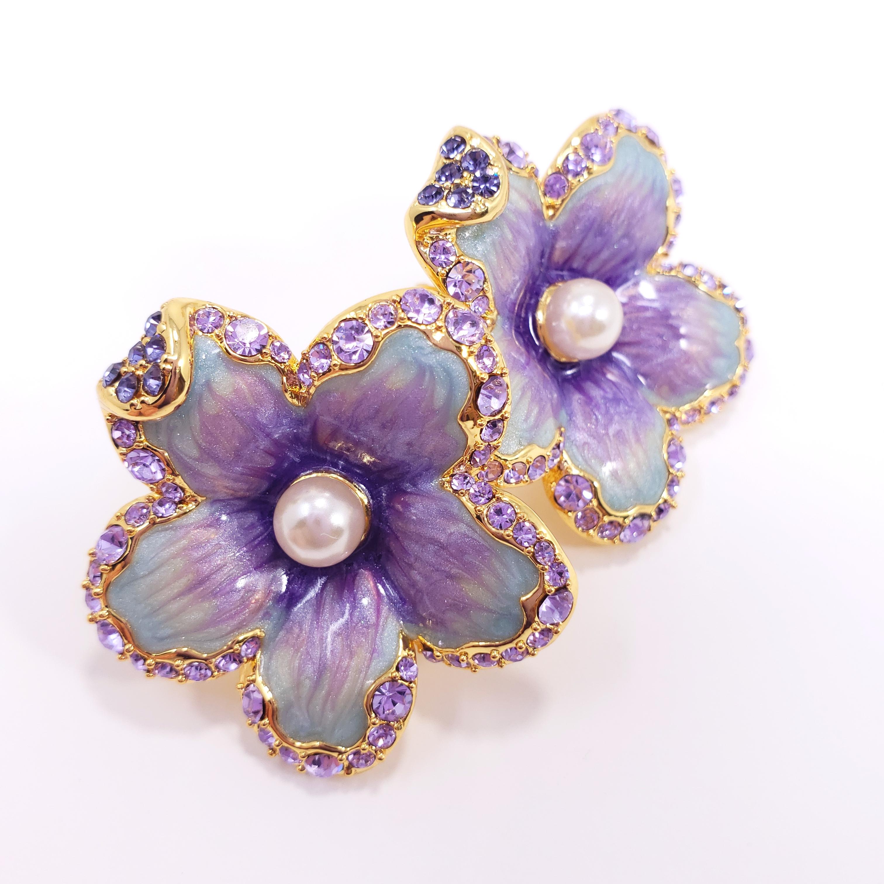 Flower power! A pair of ornate floral clip on earrings featuring lilac crystals & faux pearls. Painted with blue and lilac enamel. Set on gold plated metal.

Hallmarks: Jay, Jay Strongwater, CN

By Jay Strongwater, originally for HSN.