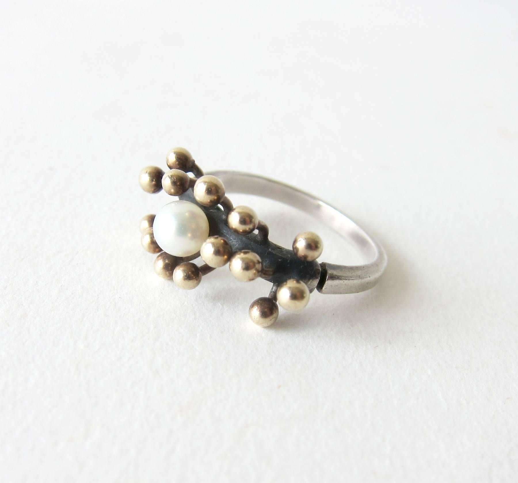 Sterling silver ring with 18k gold spores surrounding a freshwater pearl created by Jay Tuttle of San Jose, California.  Ring is a finger size 6.5 to 6.75 and is signed Tuttle, Sterling.  An unconventional alternative to a modern day engagement