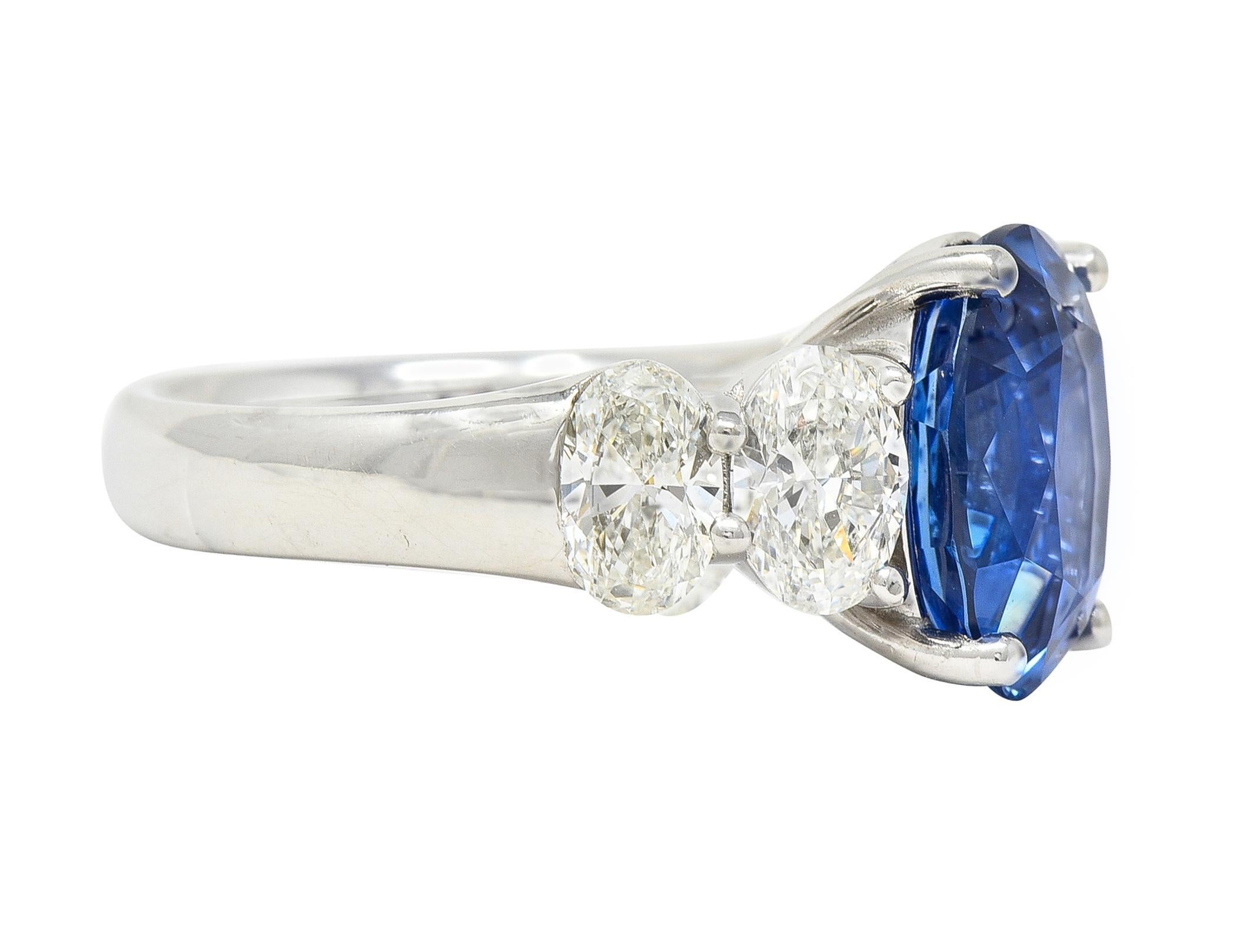 Centering an oval cut sapphire weighing 5.31 carats - transparent vibrant blue 
Natural Sri Lankan in origin - prong set in basket and flanked by diamonds 
Oval cut and weighing approximately 1.84 carats total 
L color with VS2 clarity - prong set