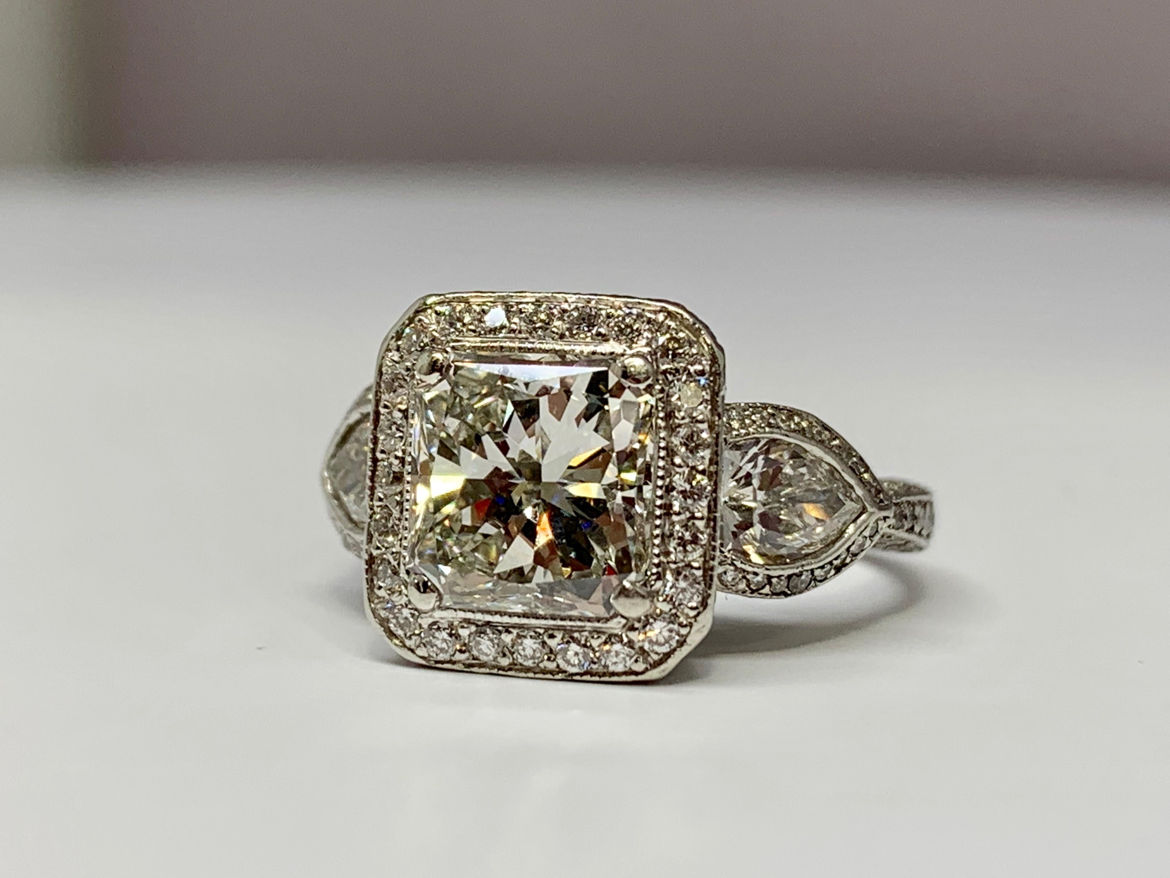 This breathtaking platinum three stone ring designed by JB Star holds a gorgeous center radiant-cut diamond weighing 2.10 carats. The quality of the center stone is approximately H/VS1. The mounting hold a total diamond weight of 1.60 carats,