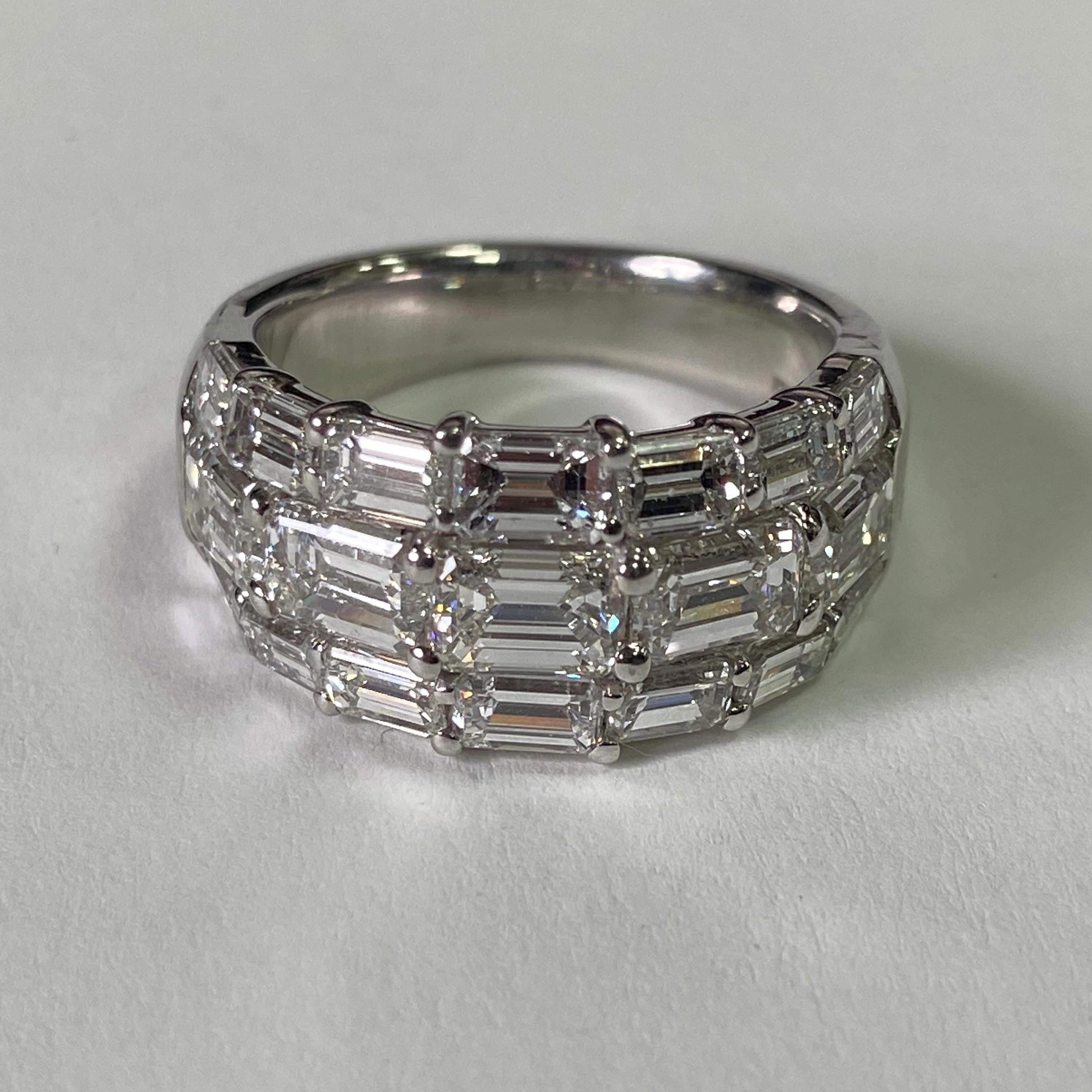 This JB Star platinum diamond band is designed with three rows of horizontal emerald cut G color, VS clarity diamonds. The center row features five larger diamonds with 2.88 total carats, while the top and bottom rows have 14 diamonds totaling 1.63
