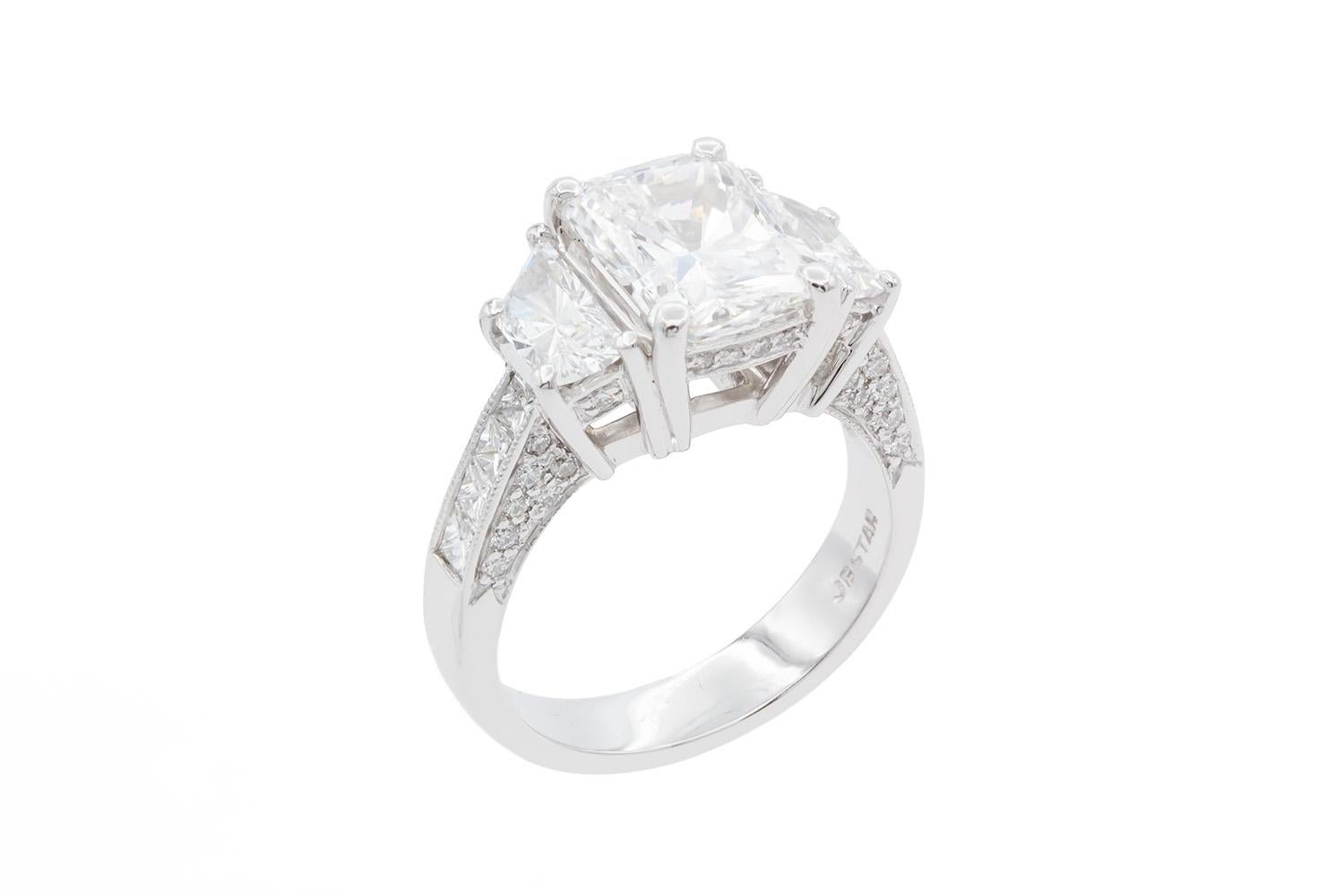 We are pleased to offer this JB Star Platinum & Radiant Cut Diamond Three Stone Engagement Ring. This stunningly beautiful ring features a GIA Certified 3.22ct E/SI1 Radiant cut diamond center stone set between two Trapezoid cut diamonds totaling