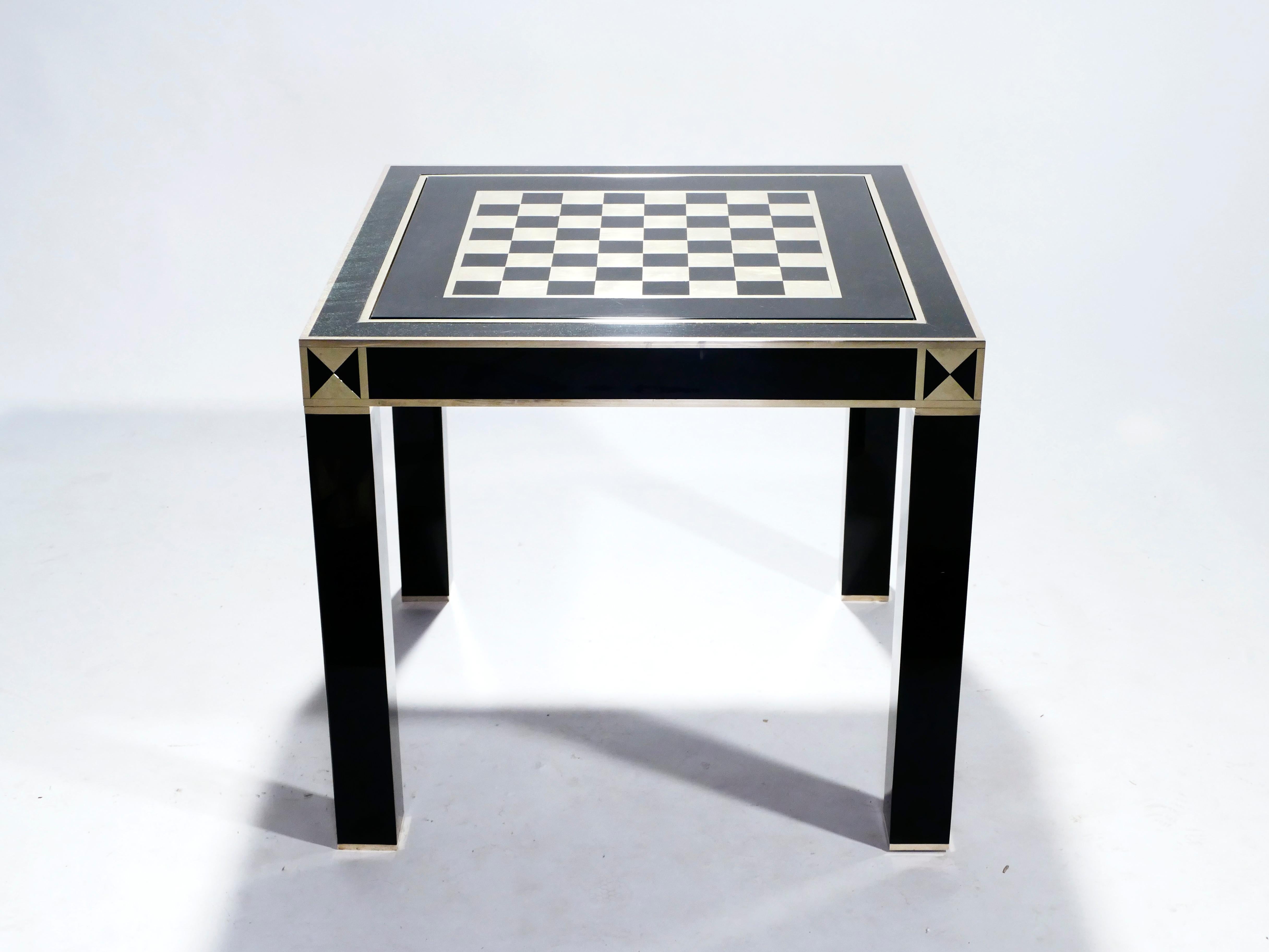 A rare game table by Jean Claude Mahey, it has a double-sided surface (green felt and a brass–lacquer checkerboard) which removes to reveal a backgammon playing surface. With its sophisticated black lacquer and shiny brass accents, the table is