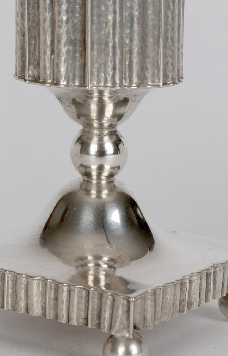 A stylish German jugendstil silver dwarf candlestick by JD Schleissner Sohne and dating from around 1910. The candlestick is mounted on a square base raised on four ball shaped feet with a ridged edge and domed centre supporting a cylindrical candle