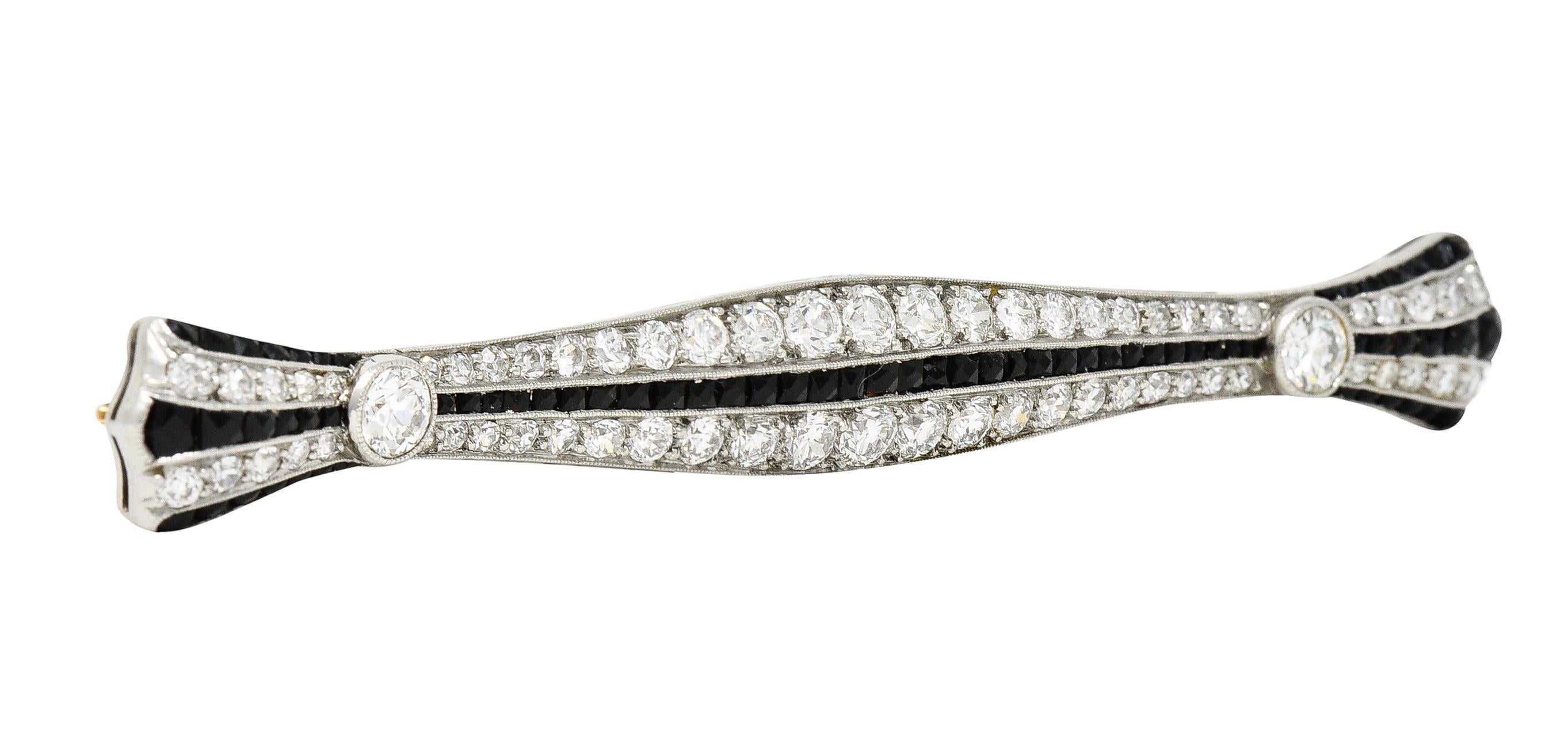 Bar brooch is designed East to West with an undulating but symmetrical profile and scalloped terminals. Profile cinches at two well matched and bezel set old European cut diamonds. Weighing in total approximately 0.40 carats with H/I color and VS