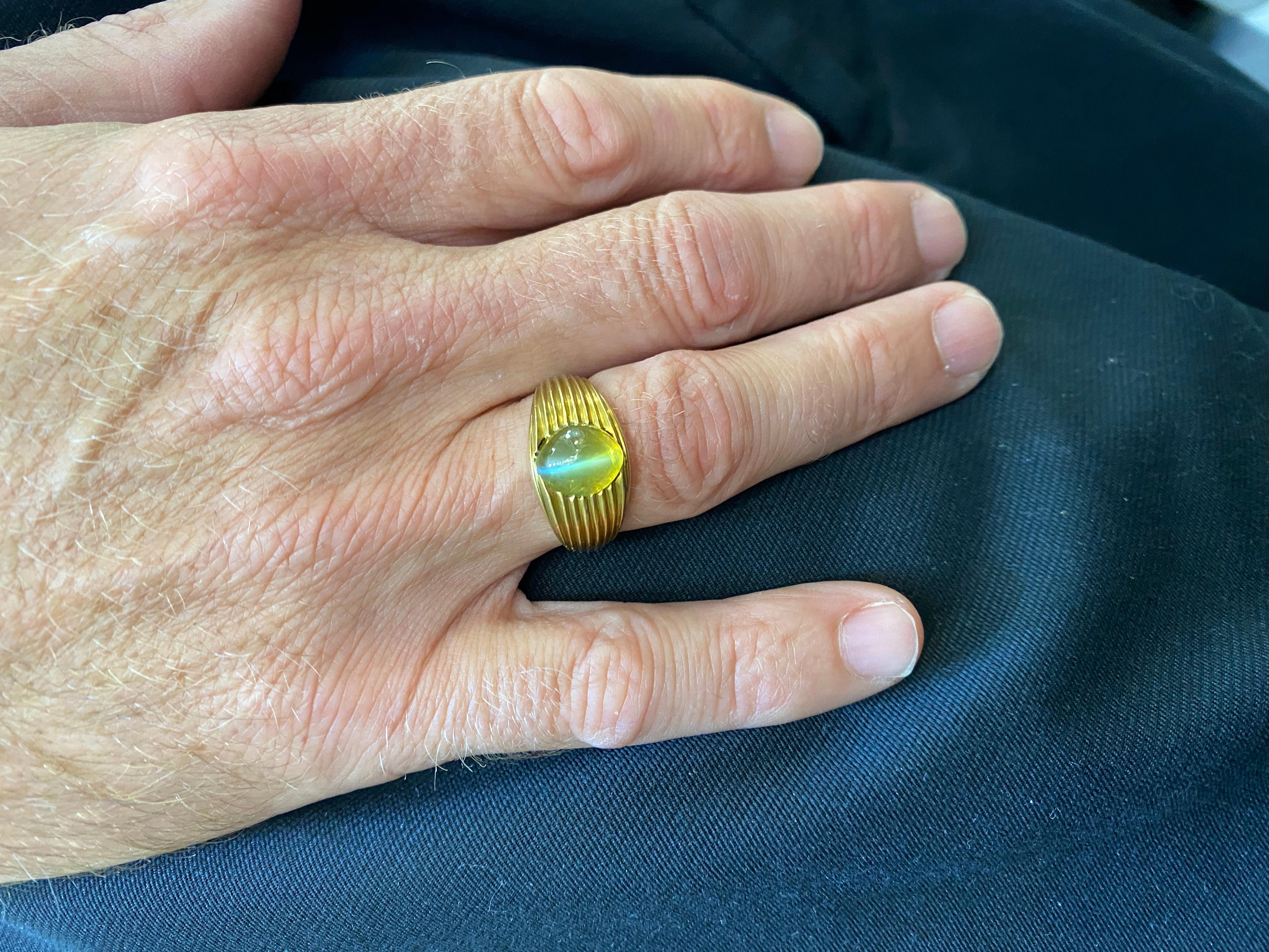 Cat's Eye chrysoberyl men's ring by designer J.E. Caldwell fashioned in 18 karat yellow gold. The Cat's Eye oval cabochon gemstone weighs approximately 6.0 carats and is certified by the AGL. There has been no treatment or enhancement to the