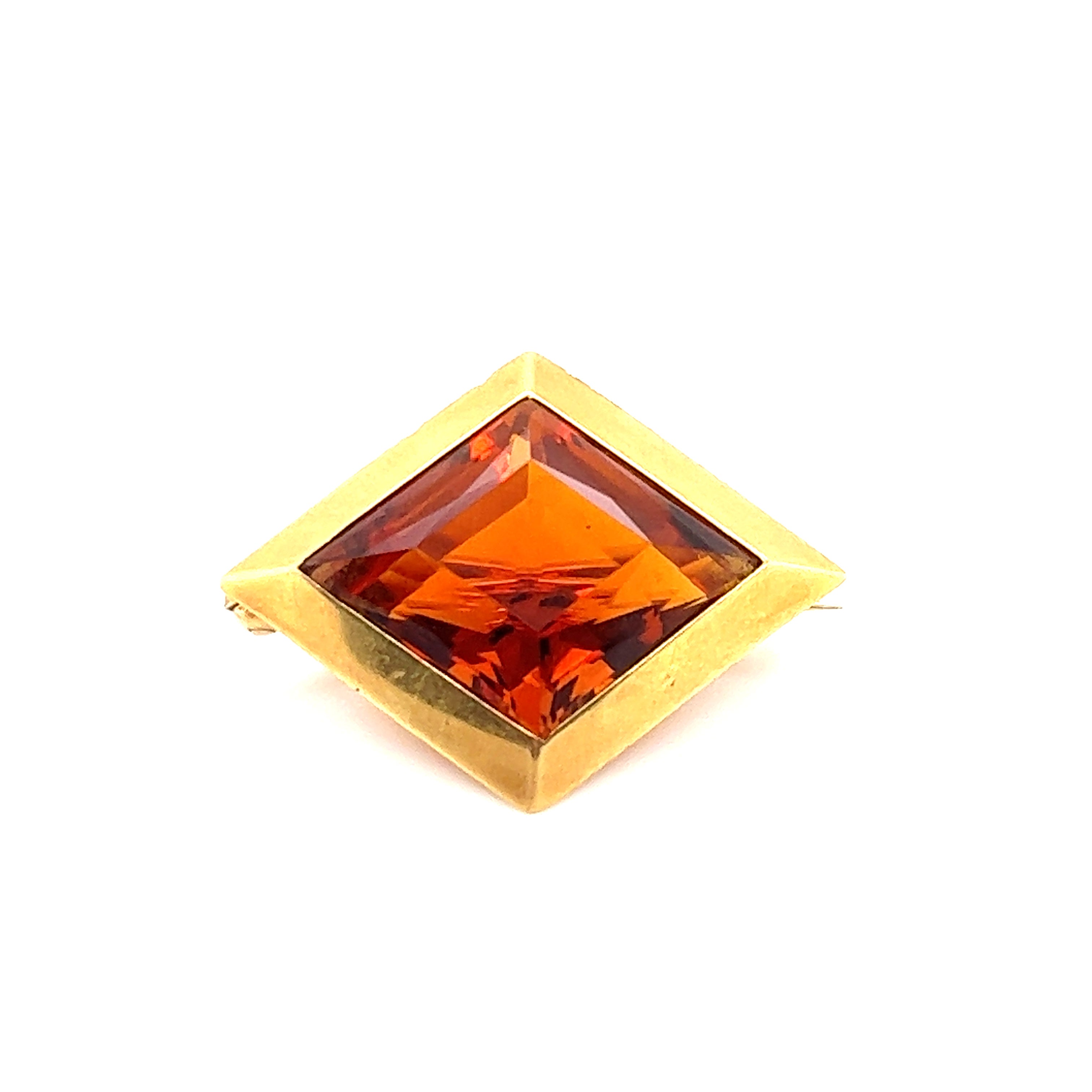 One geometric shaped shield brooch by famed jewelry house J.E. Caldwell & Co. The brooch is set with one Madeira Citrine gemstone in a lozenge shape. The gemstone is bezel set in the design showing sharp edges at each corner. The 18k gold border