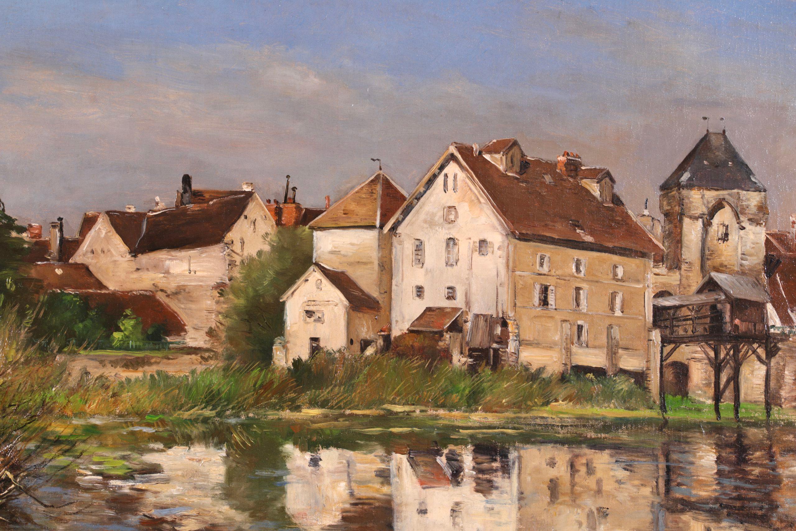 Signed oil on canvas landscape circa 1890 by French impressionist painter Jean Baptiste Antoine Guillemet. The work depicts a view of Moret-sur-Loing in North Eastern France from the bank of the River Loing. The town's buildings are reflecting in