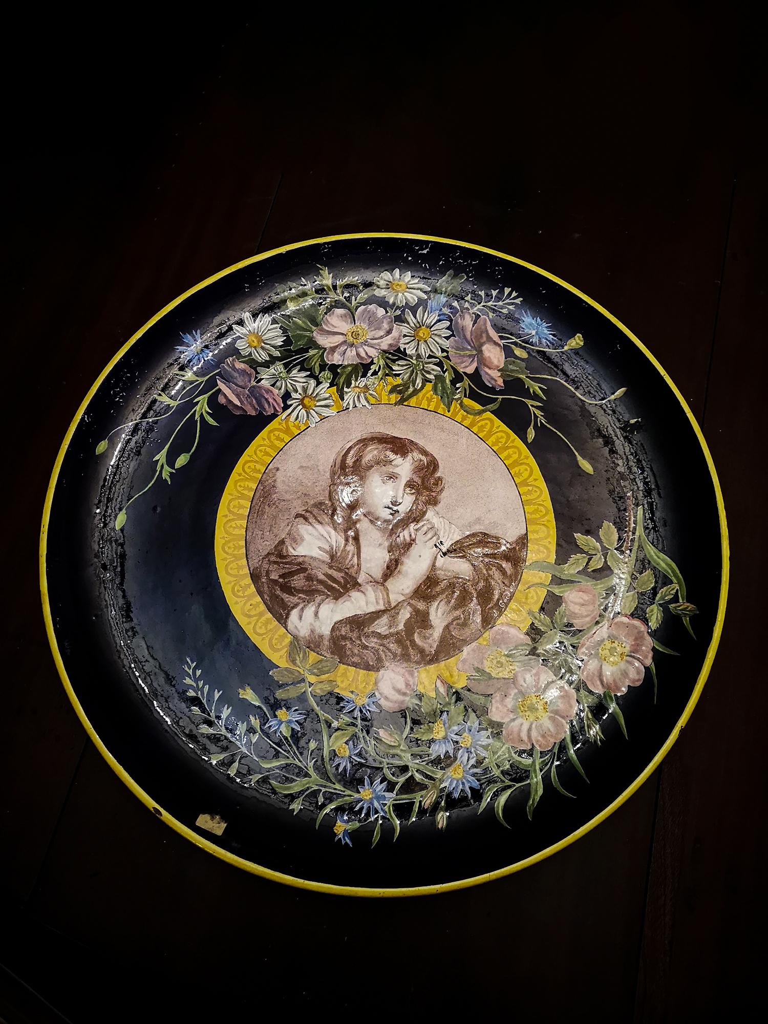 A large round platter platter of Limoges porcelain with gold decoration, delicate arabesques and flowers and a woman in the center painted after the artist Jean-Baptiste Greuze (Tournus 1725-1805 Paris) made in the  Vincennes Porcelain foundry of 