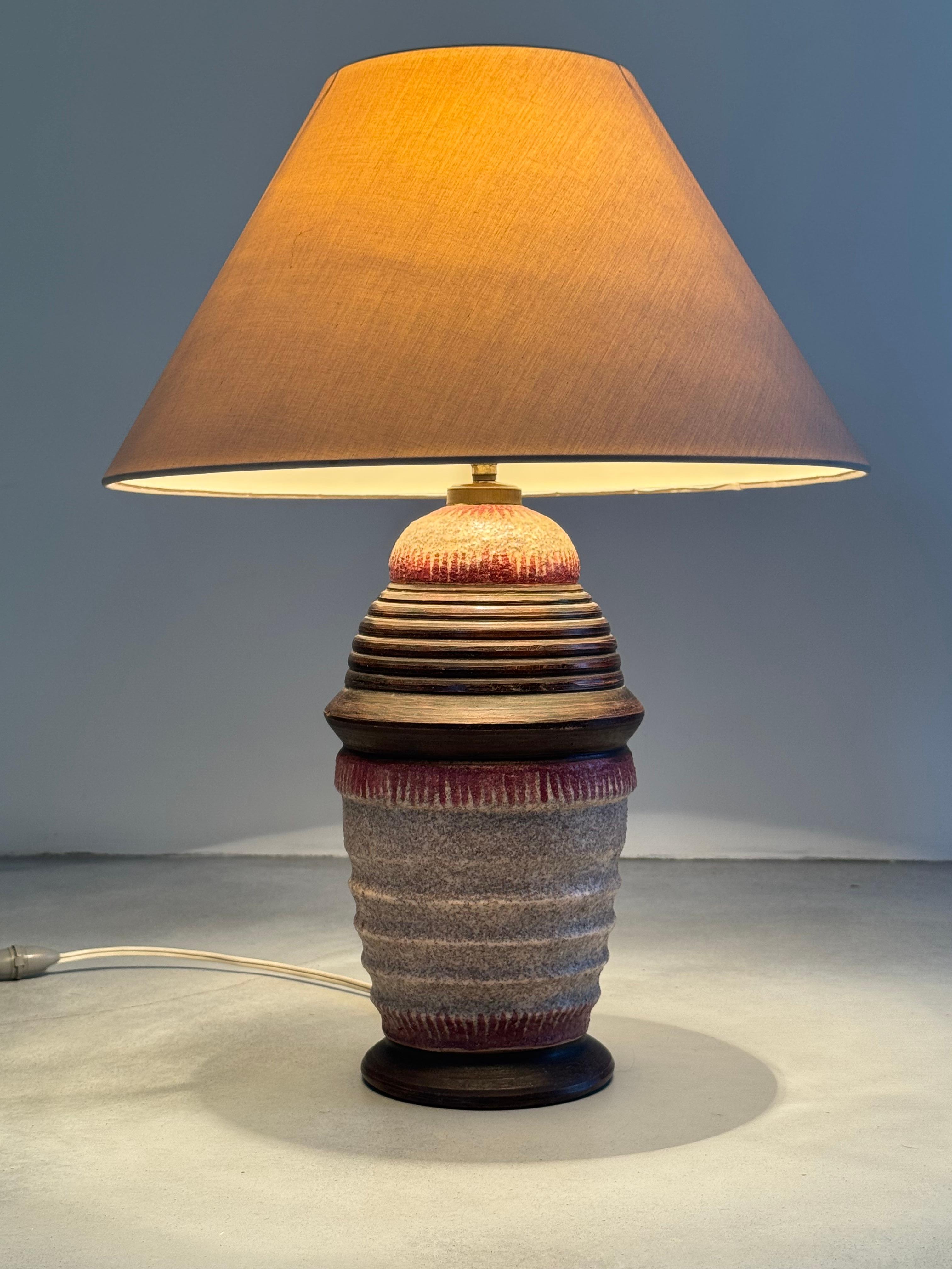 Très jolie lampe de table en céramique émaillée et texturée, la panse est décorée de frises de vaguelettes.

Œuvre attribuée à l'artiste céramiste français Jean Besnard, période Art déco.

La lampe est en très bon état, l'usure correspondant à l'âge