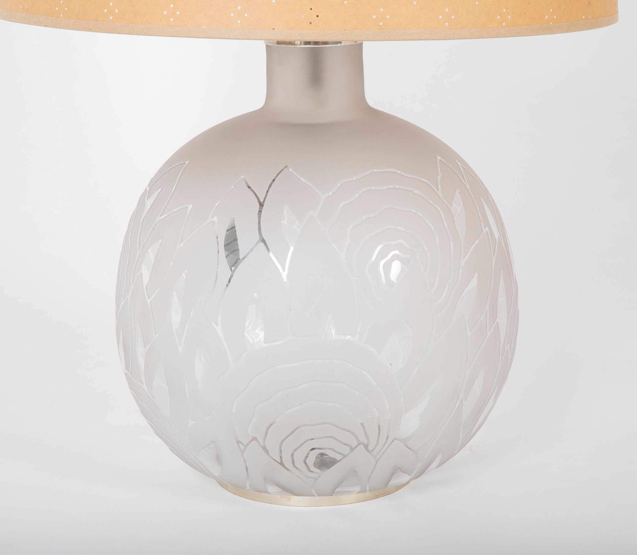 Eine abgenutzte Lampe aus säuregeätztem Glas mit vernickelten Halterungen von Jean Boris Lacroix ( Frankreich, 1902 - 1984 ). Die Liebe zum Detail setzt sich in der geätzten Signatur und der asymmetrischen Montage auf dem Sockel fort. Die Lampe ist
