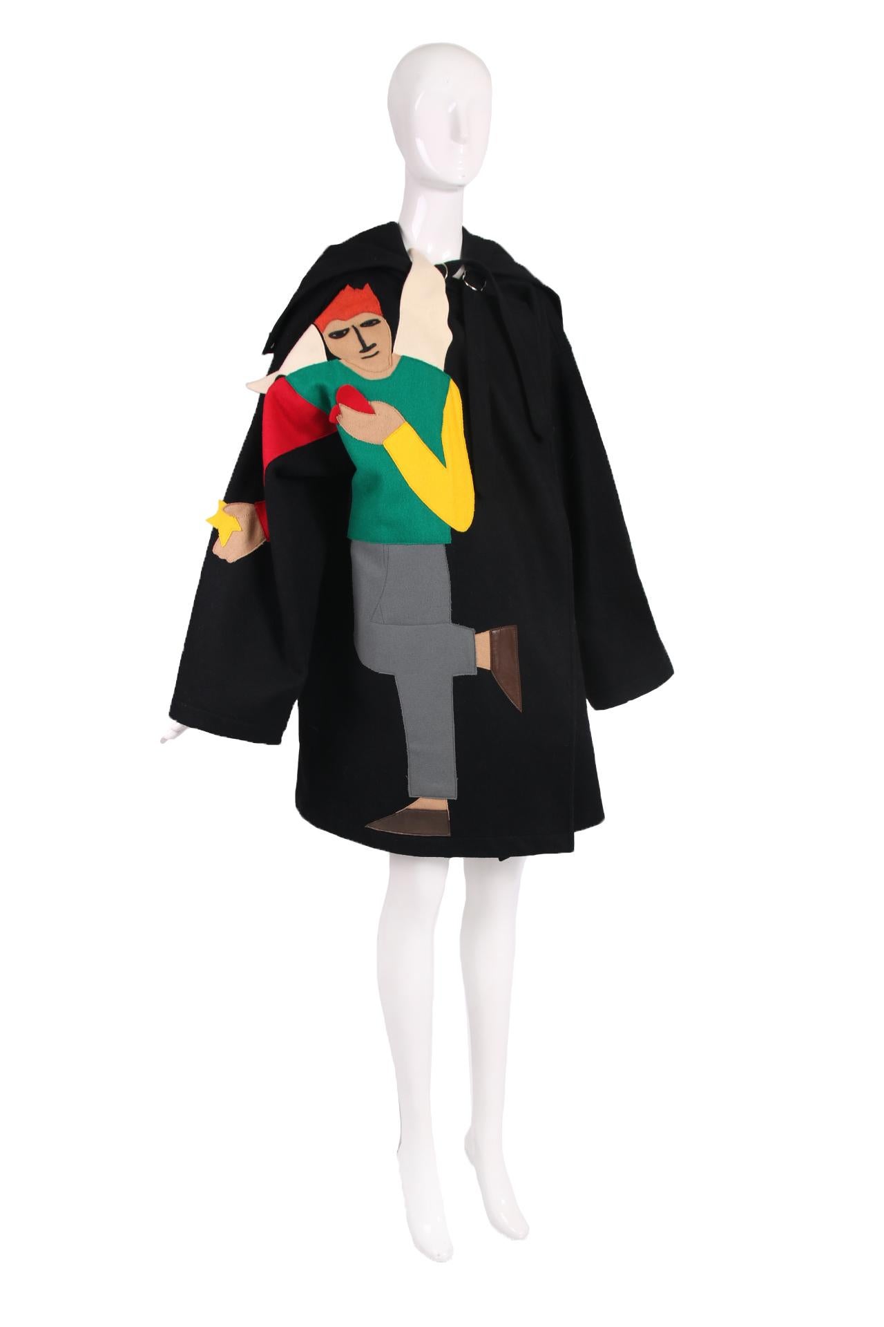 Raro cappotto oversize in lana melton nera di Jean-Charles De Castelbajac con un uomo alato dai capelli rossi che indossa stivali in pelle e tiene un cuore rosso in una mano e una stella gialla nell'altra. Ha tasche laterali nascoste, un colletto