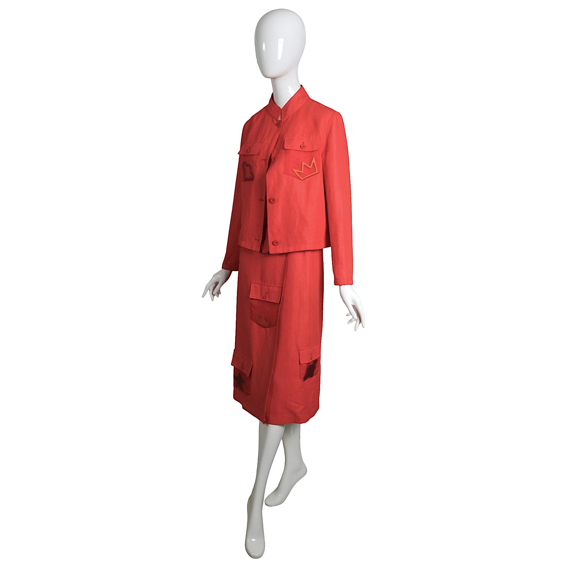 This striking vintage 1980s set by Jean-Charles de Castelbajac captures the designer's signature playful aesthetic. Crafted from vibrant coral linen, the ensemble includes a jacket and a chic wrap skirt, 
The jacket and skirt feature unique pockets