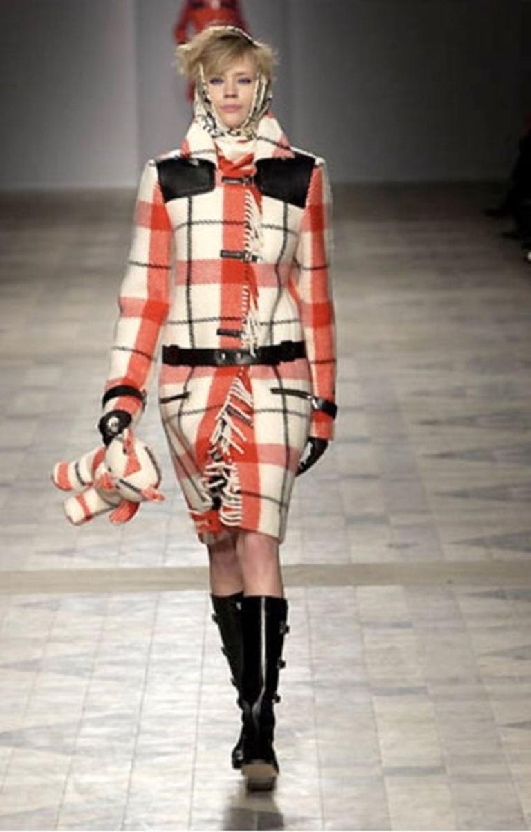 JC DE CASTELBAJAC - Cappotto in lana filata con motivo a quadri color crema, nero e rosso. Bordi e cintura in pelle nera. Chiusura e frange in metallo argentato. Viene fornito con un cappotto per cani dello stesso tessuto. Taglia 42FR indicata.