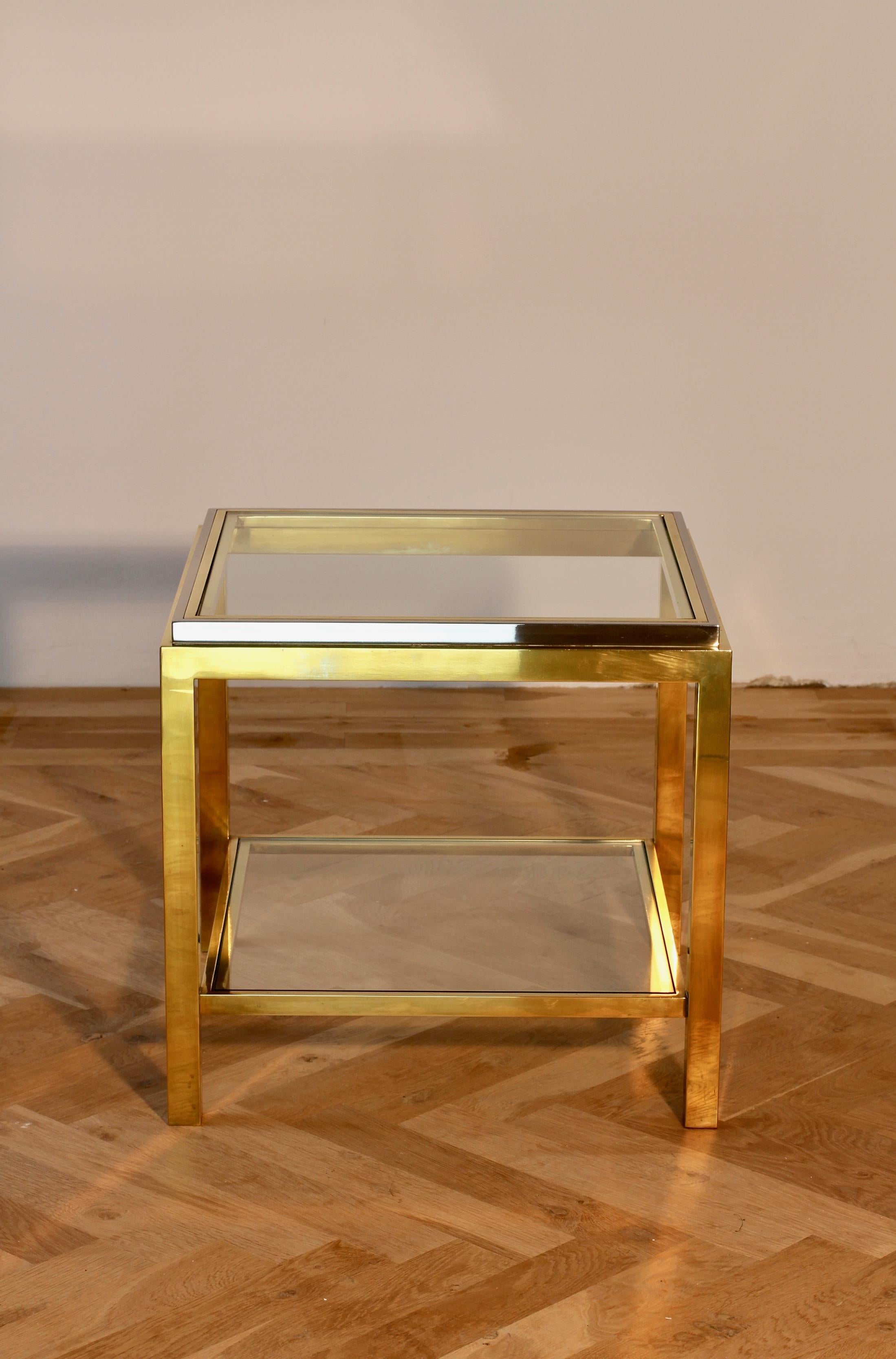 Signed Jean Charles two-tiered brass and chrome-plated side or end table, circa 1970s. Perfect for the Hollywood Regency style enthusiast or midcentury lover although, this table would sit very well indeed within any contemporary home decor