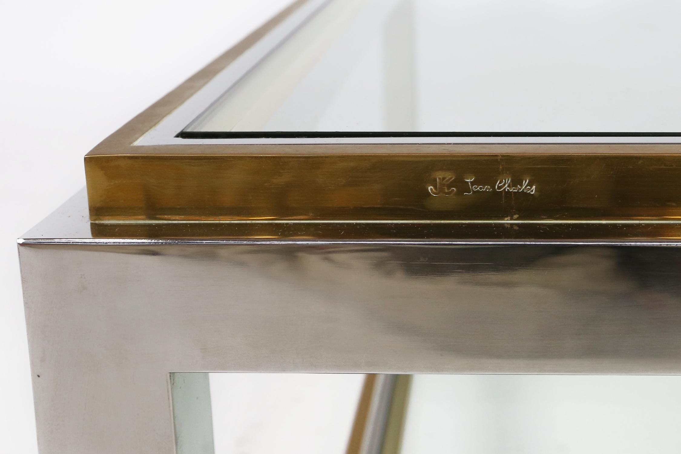 Elegant chrome and glass square coffee table in brass and chrome, designed by Jean Charles, made by Maison Charles. 
Signed and stamped Jean Charles on one side.

The table is in very good condition. Only light signs of use and age. 
  