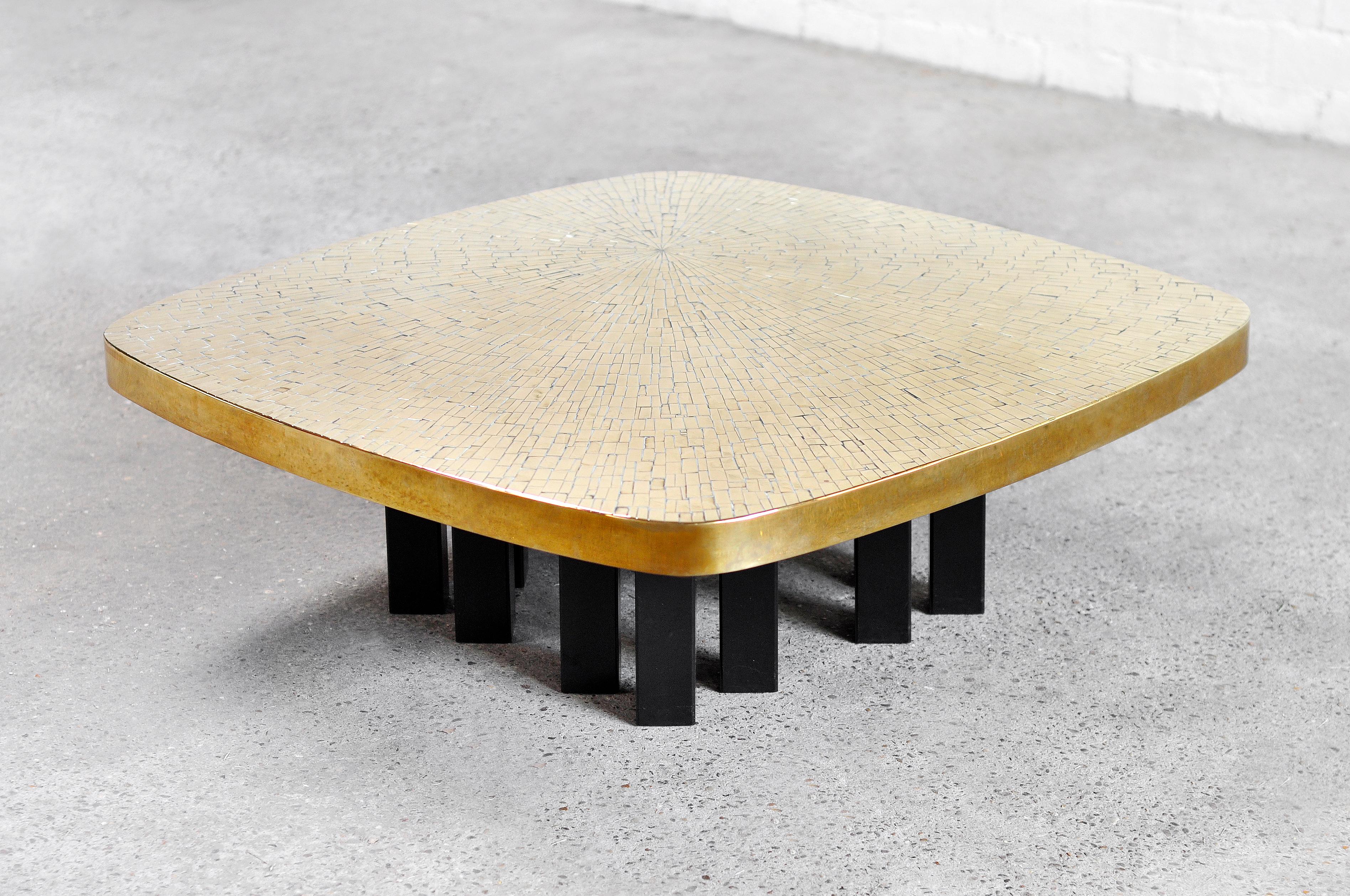 An exclusive coffee table designed and created in the workshop of Marcel and Jean-Claude Dresse in the 1970’s. The tabletop features a beautiful fragmented surface with an inlaid gilt brass mosaic. The rounded square plate sits on top of a structure