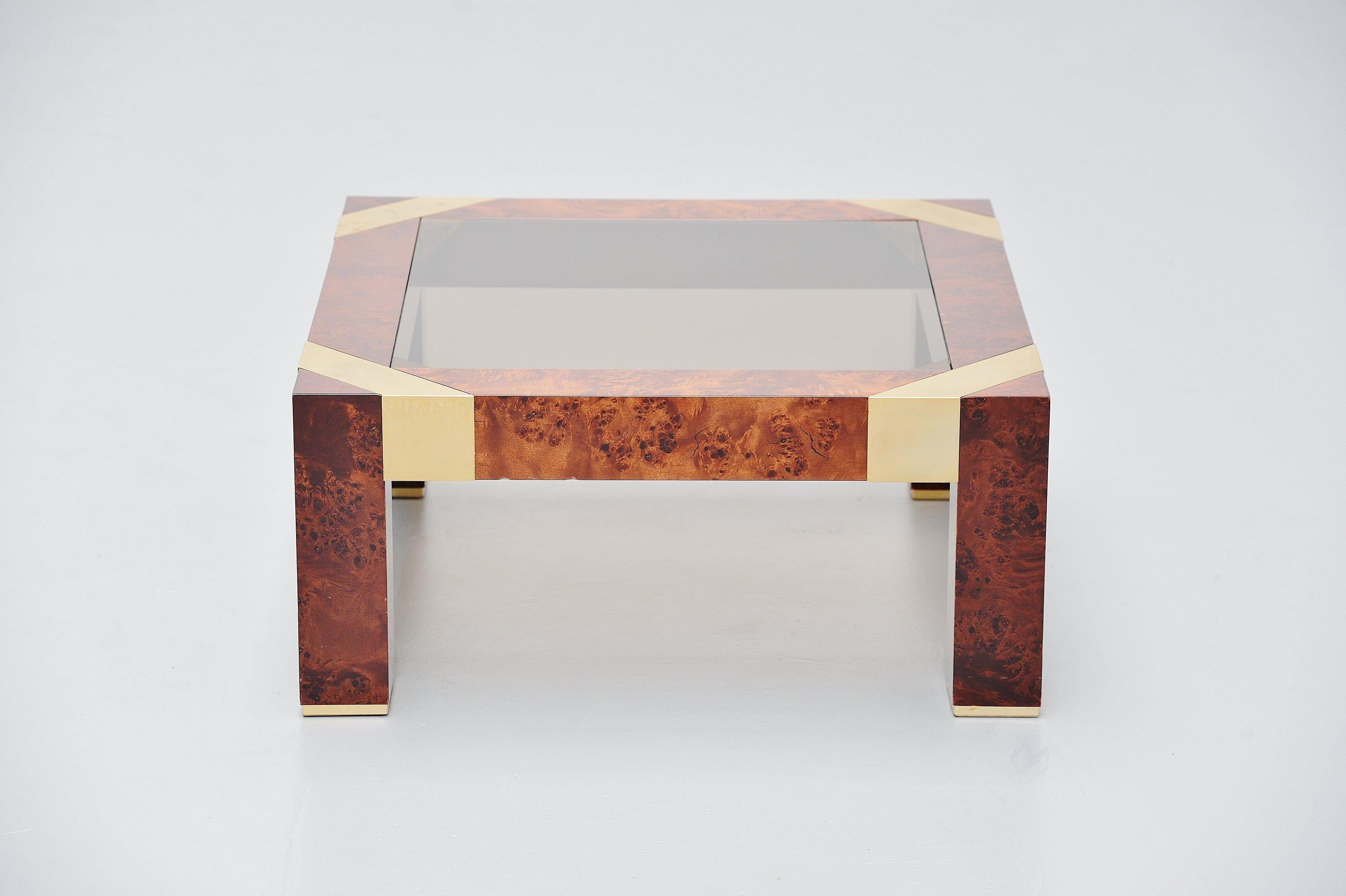 Nice Hollywood Regency style coffee table designed by Jean Claude Mahey and manufactured by Studio Mahey, France, 1970. The sofa has burl wood veneer with gloss finish. The details are made of brass plated metal and it has a smoked glass top. The