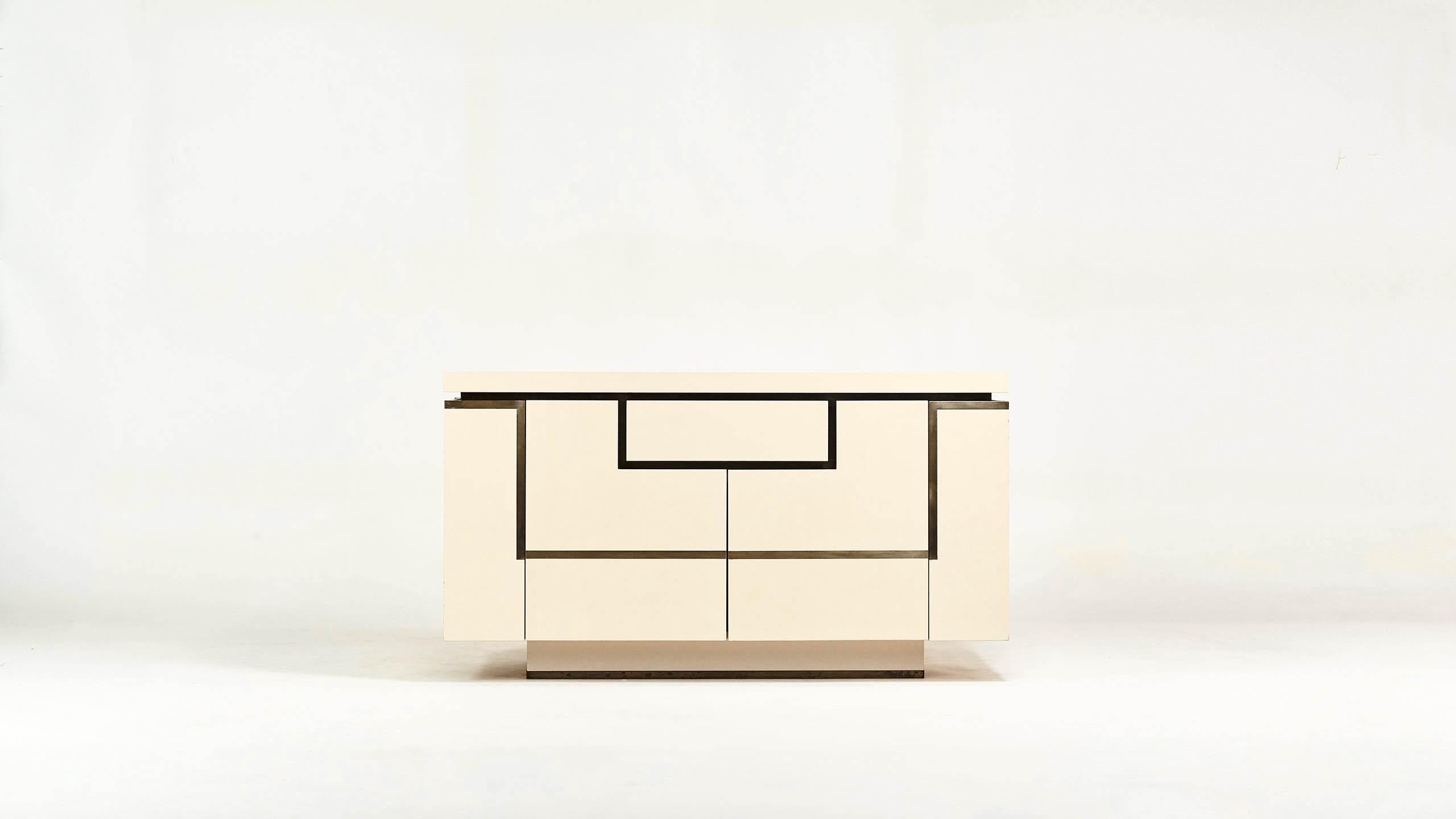Ivory lacquered wood sideboard enhanced with brass, by designer Jean-Claude Mahey for Roche Bobois. Opening with two side doors revealing bar, and 2 doors and 1 drawers in front. Small traces of use, good overall condition, circa 1970.