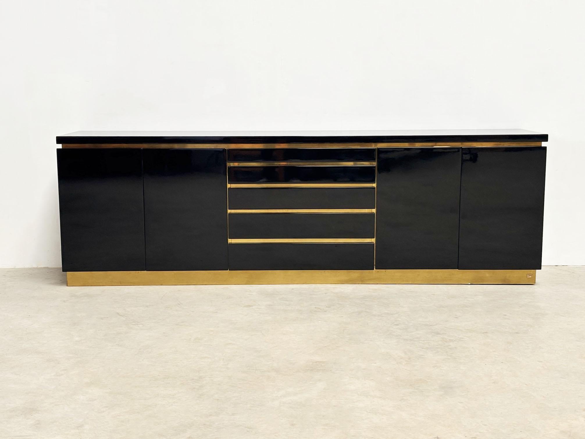 Questa lussuosa credenza del designer francese Jean Claude Mahey cattura l'essenza del glamour degli anni '70, con la sua finitura laccata lucida e gli eleganti accenti in ottone. Completamente rifinito all'esterno, è ora in perfette condizioni e