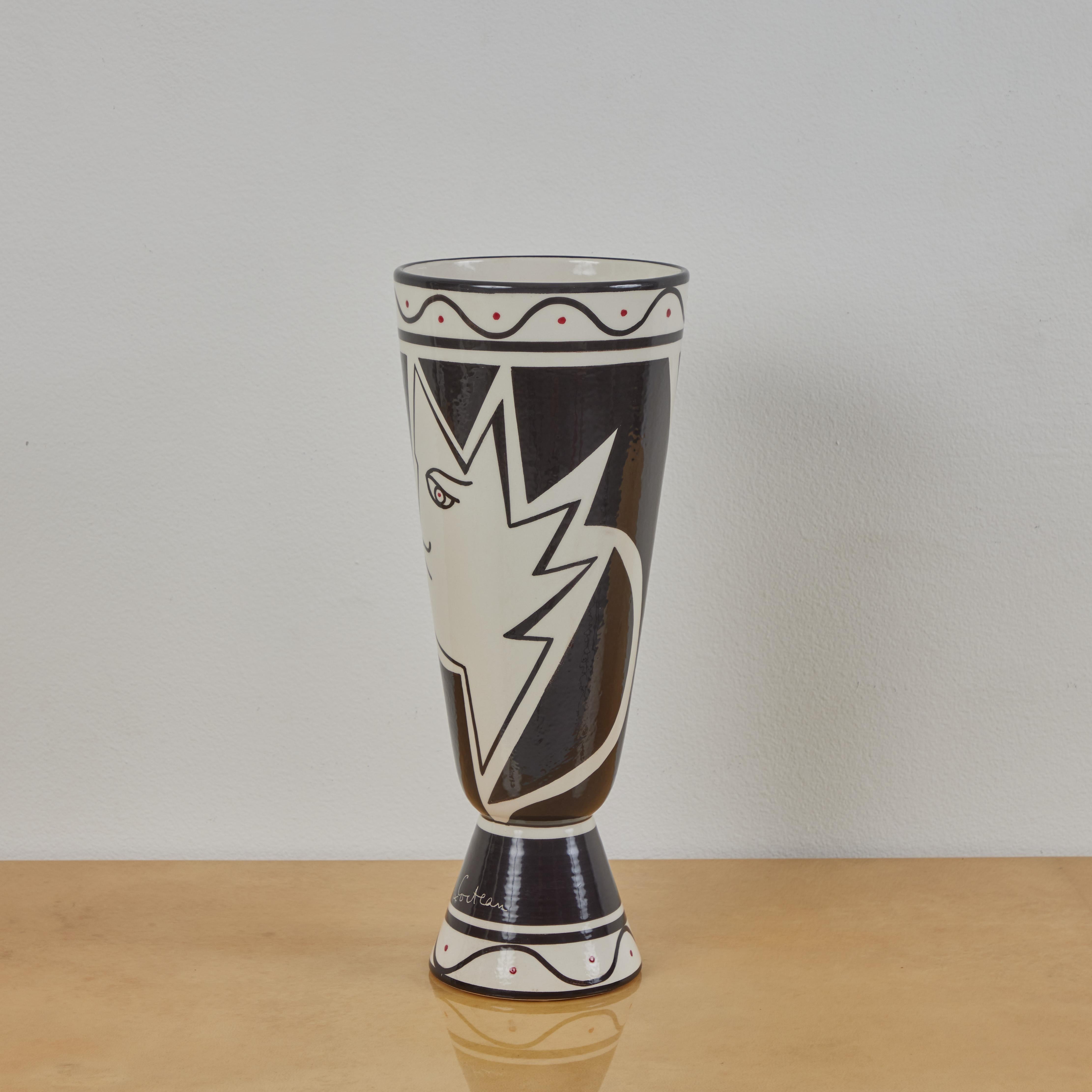 This is a decorated vase produced by Roche Bobois in the 2010s. The vase utilizes a design Jean Cocteau produced in the early 1960s. It features 2 geometric profiles with additional details painted in red. This is a limited edition of 1,000 produced
