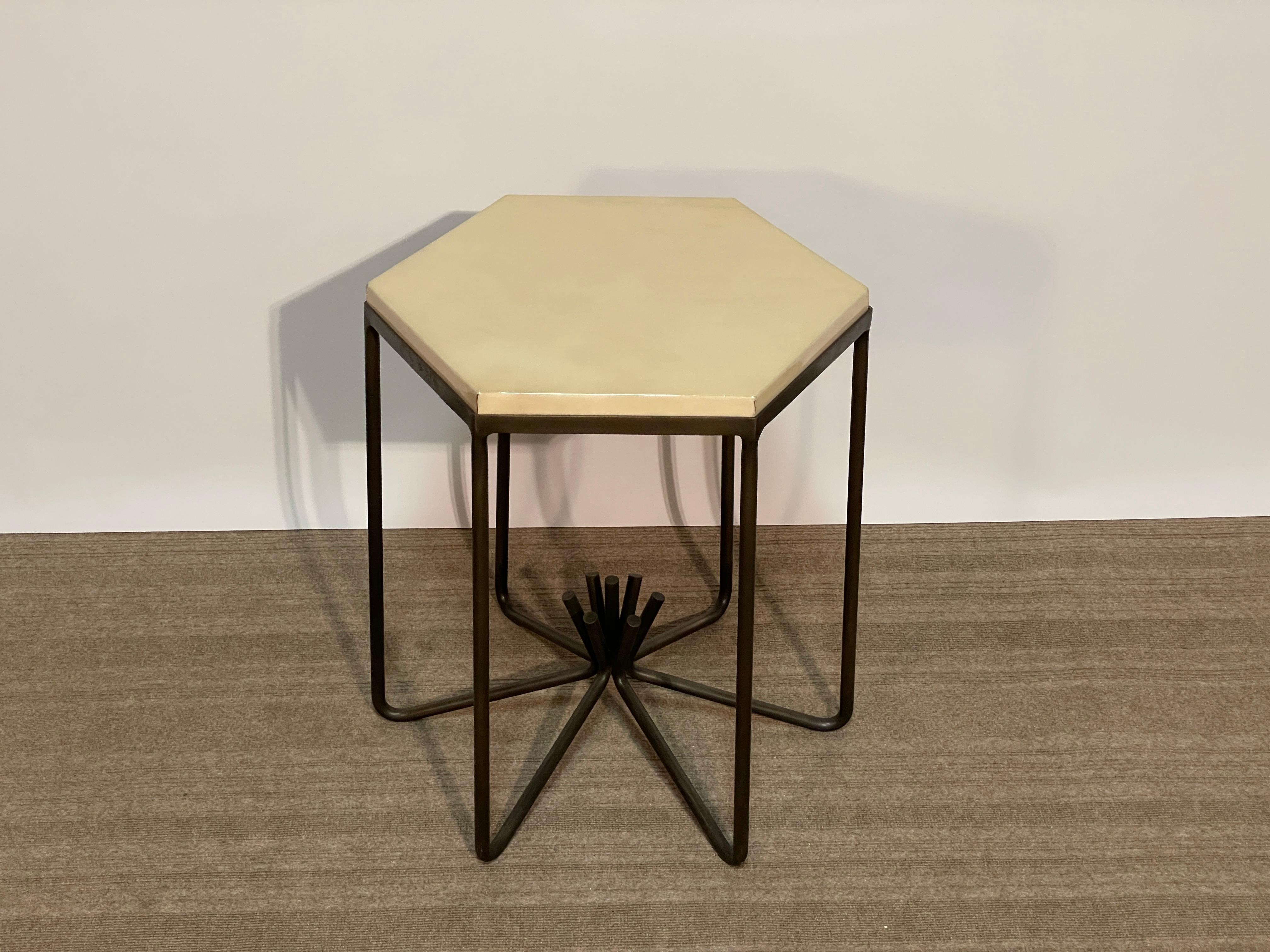 The Eileen side table by Jean de Merry is a timeless design of bent bronze shafts that collect in the center, turned up to form the sturdy base finished in antiqued bronze.  The wooden top is covered in natural parchment with a lacquer finish