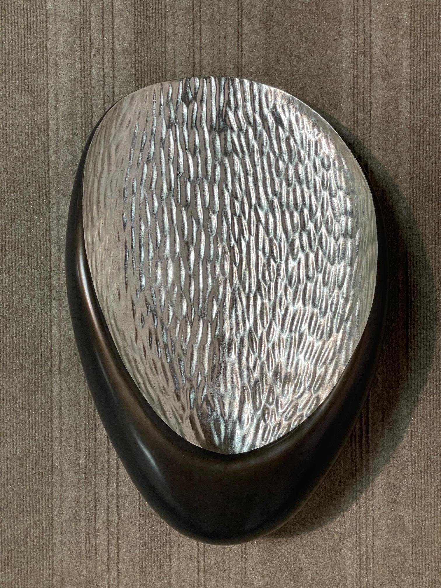 Jean de Merry's Hanna wall sconce is formed from a single hand-carved piece of wood that is painstakingly textured on the interior and smoothed on the exterior.  An almost oceanic presence prevails amidst the sparkling white gold interior contrasted